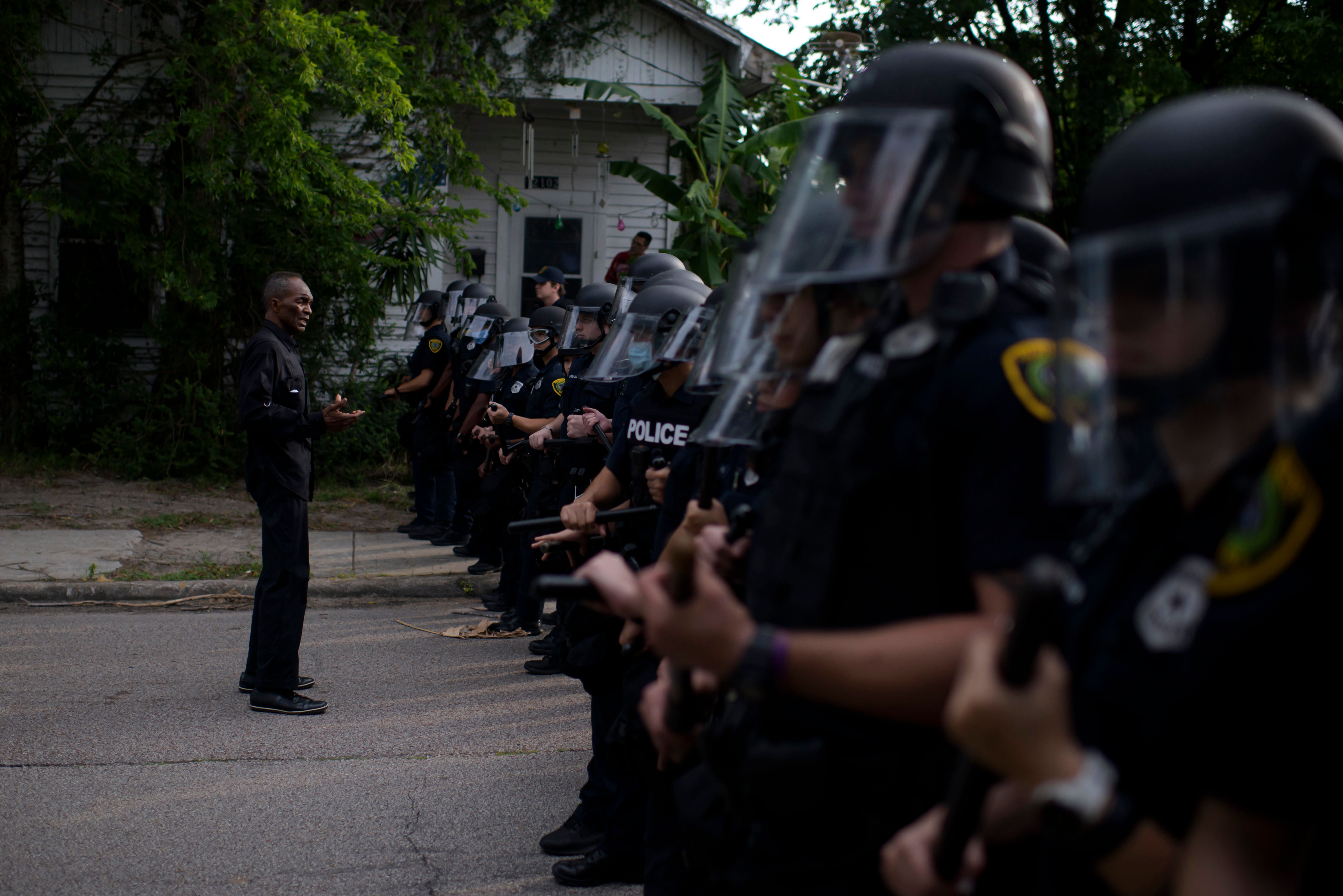 A man addresses a row of police officers during a "Justice for George Floyd" event in Houston, Texas on May 30, 2020, after George Floyd, an unarmed black, died while being arrested and pinned to the ground by a Minneapolis police officer. - Clashes broke out and major cities imposed curfews as America began another night of unrest Saturday with angry demonstrators ignoring warnings from President Donald Trump that his government would stop violent protests over police brutality "cold." (Photo by MARK FELIX/AFP via Getty Images)