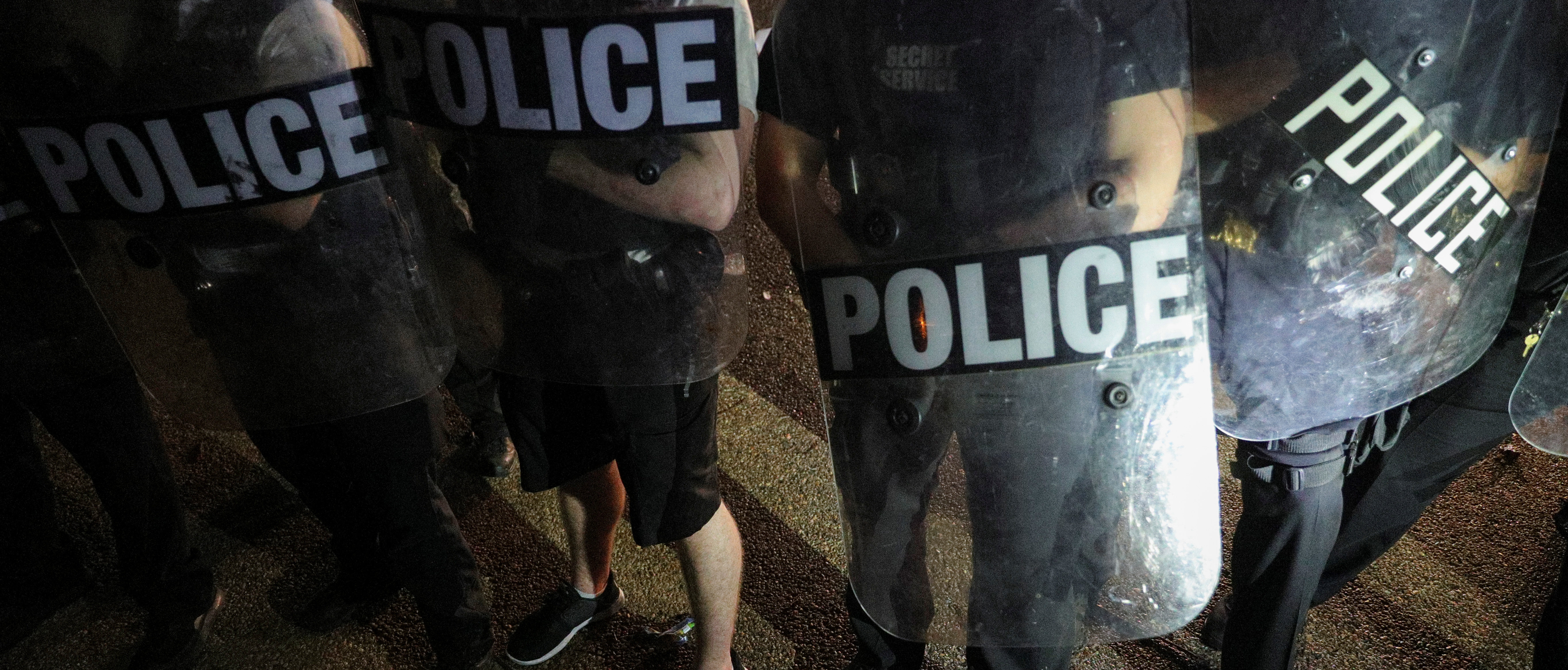U.S. Secret Service uniformed division officers holding riot shields stand among water bottles and other object thrown at them after midnight by a crowd demonstrating against the death in Minneapolis police custody of African-American man George Floyd, as the officers keep demonstrators away from the White House during a protest in Lafayette Park in Washington, U.S. May 30, 2020. REUTERS/Tom Brenner 