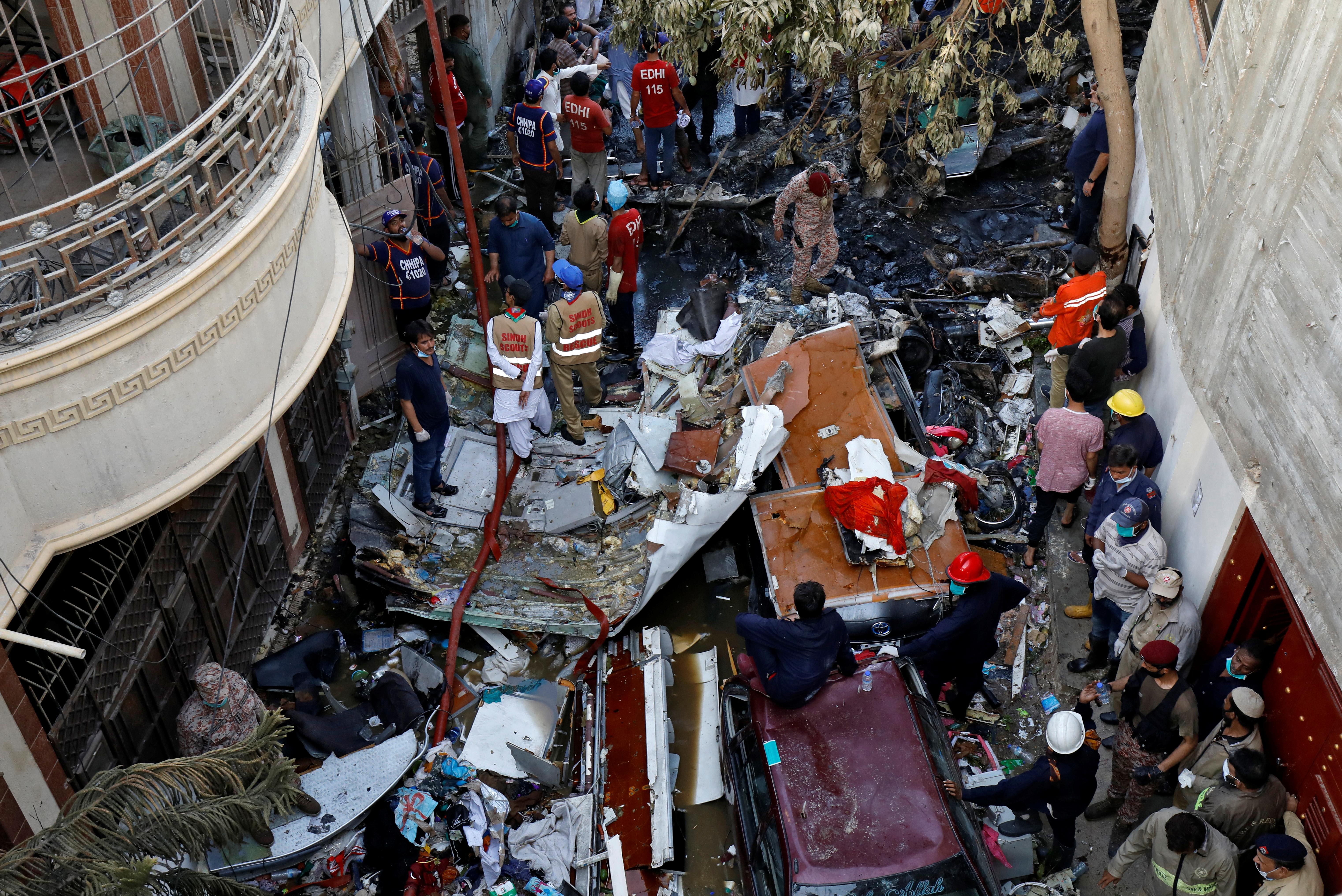 Rescue workers gather at the site of a passenger plane crash in a residential area near an airport in Karachi, Pakistan May 22, 2020. REUTERS/Akhtar Soomro - RC2PTG9FEVAS