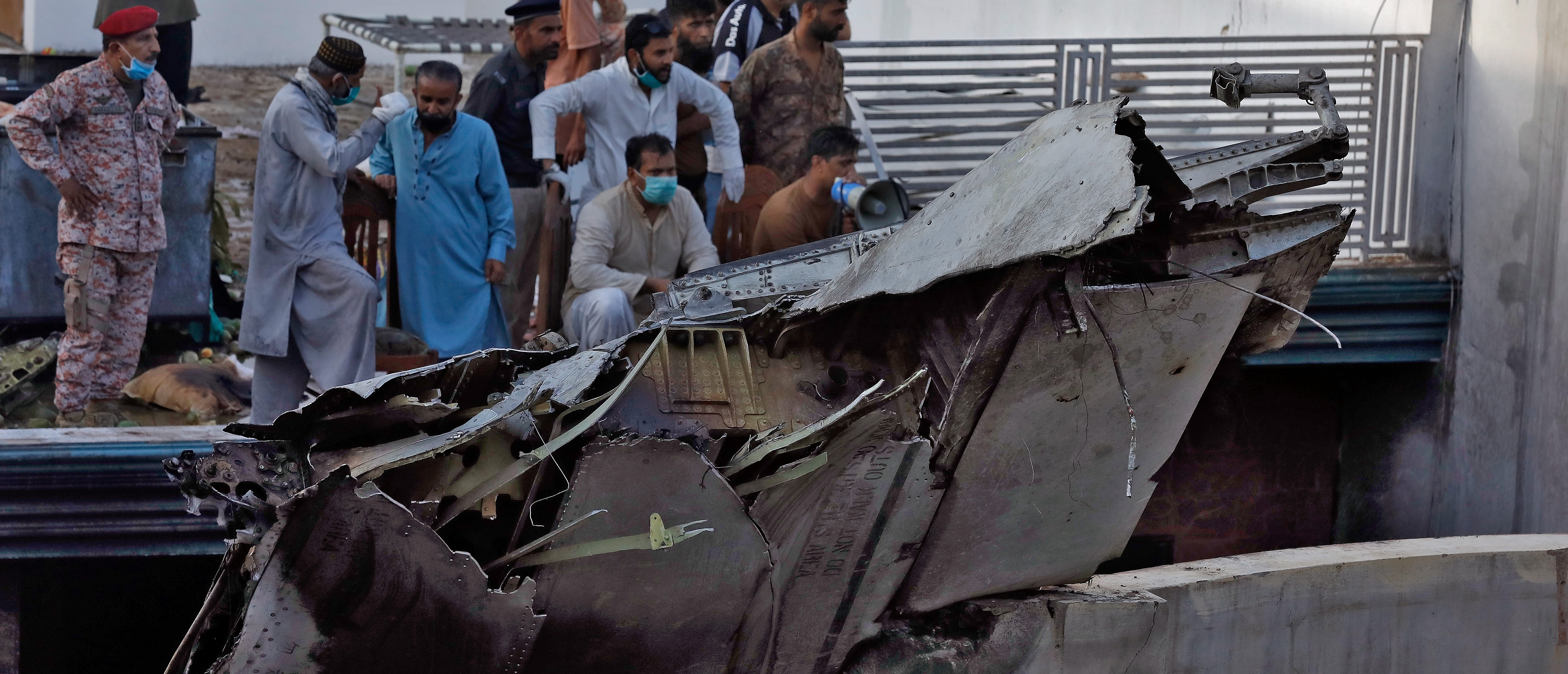 People stand next to the debris of a plane after crashed in a residential area near an airport in Karachi, Pakistan May 22, 2020. REUTERS/Akhtar Soomro - RC2PTG9N20SG