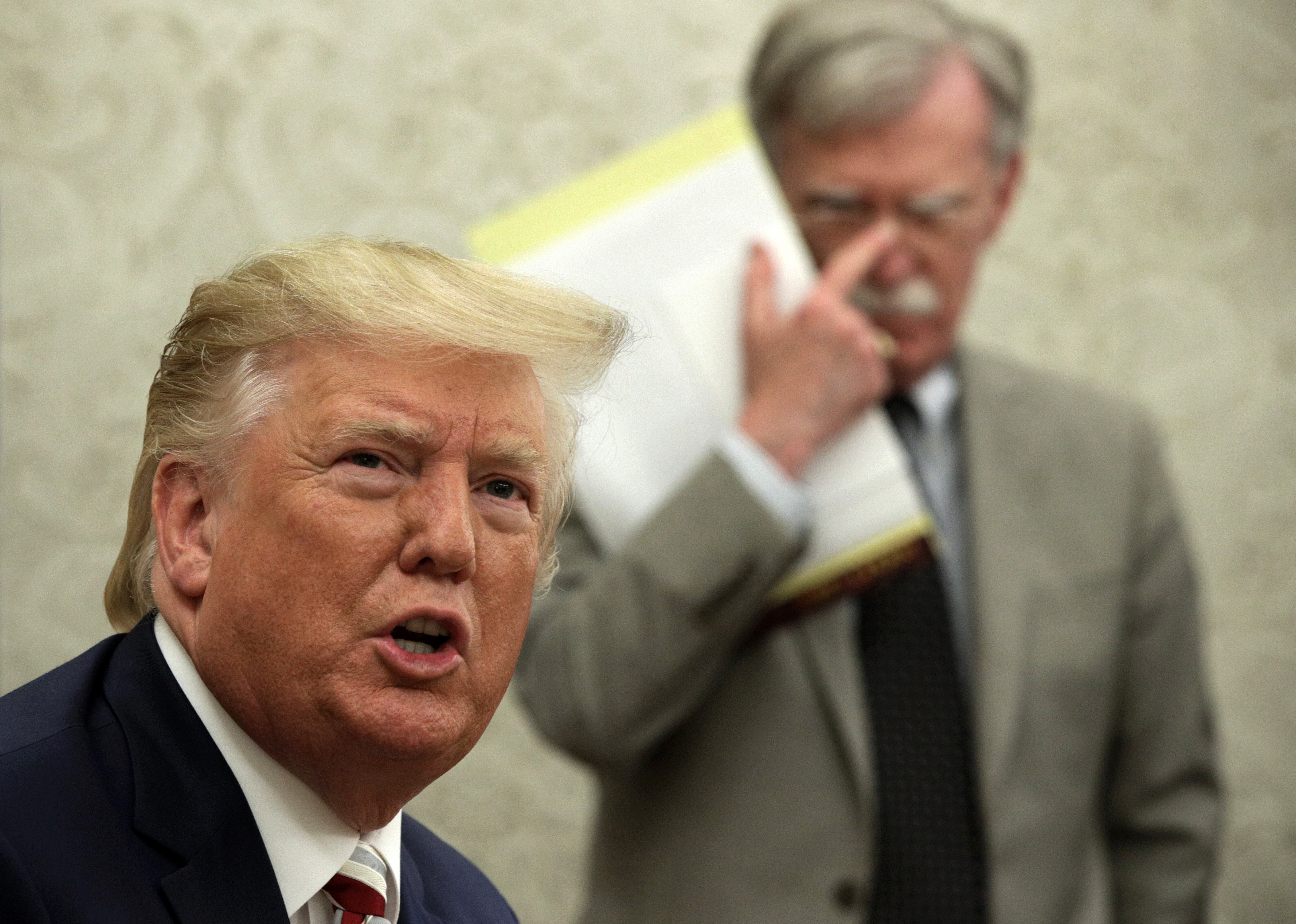 WASHINGTON, DC - AUGUST 20: U.S. President Donald Trump speaks to members of the media as National Security Adviser John Bolton listens during a meeting with President of Romania Klaus Iohannis in the Oval Office of the White House August 20, 2019 in Washington, DC. This is Iohannis’ second visit to the Trump White House and the two leaders are expected to discuss bilateral issues during their meeting. (Photo by Alex Wong/Getty Images)