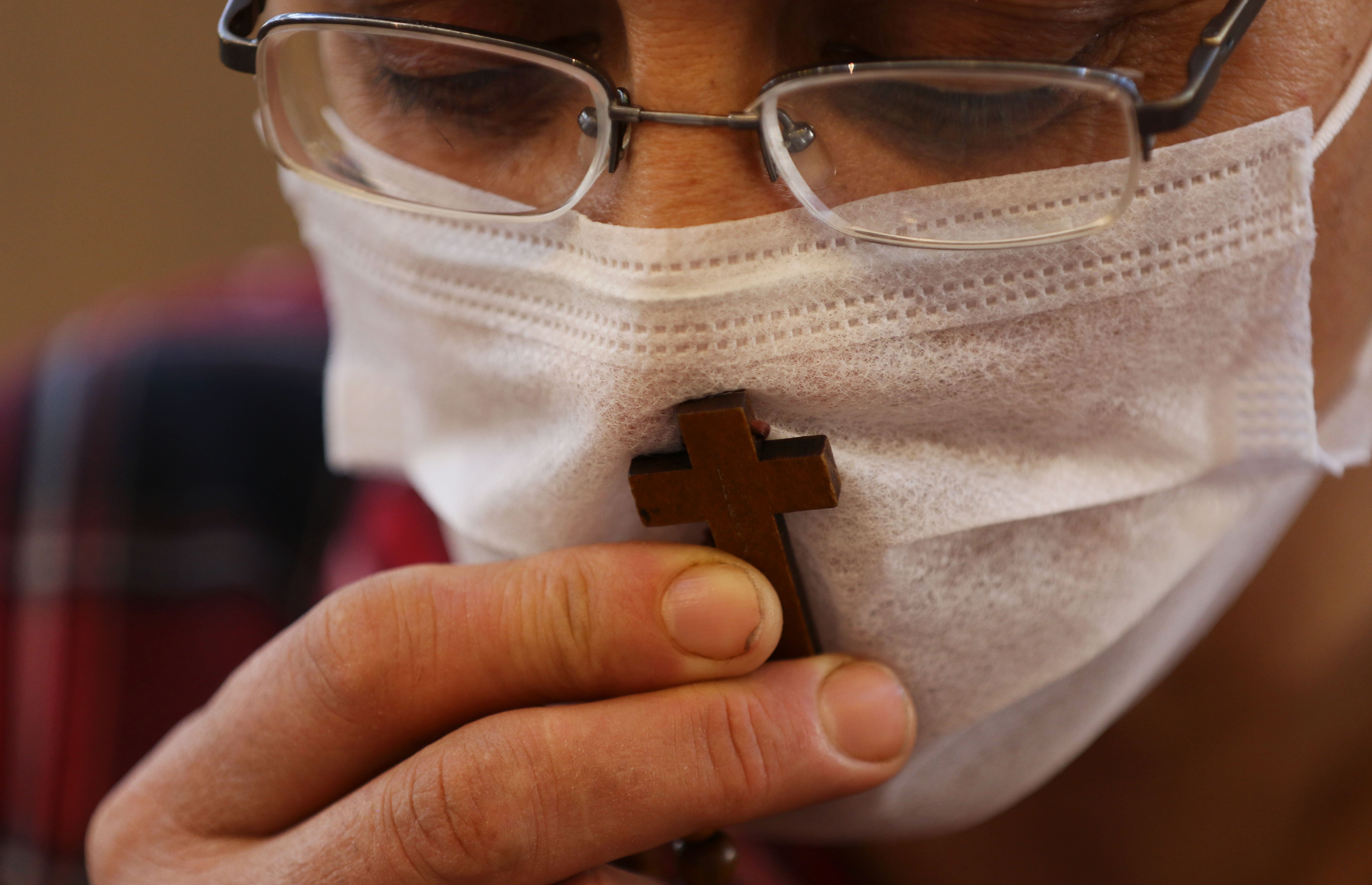 A Christian worshipper, wearing a protective mask due to the COVID-19 pandemic, kisses a cross as he prays at the Mart Shmoni church in Arbil, the capital of the autonomous Kurdish region of northern Iraq, on May 17, 2020. (Photo by SAFIN HAMED/AFP via Getty Images)
