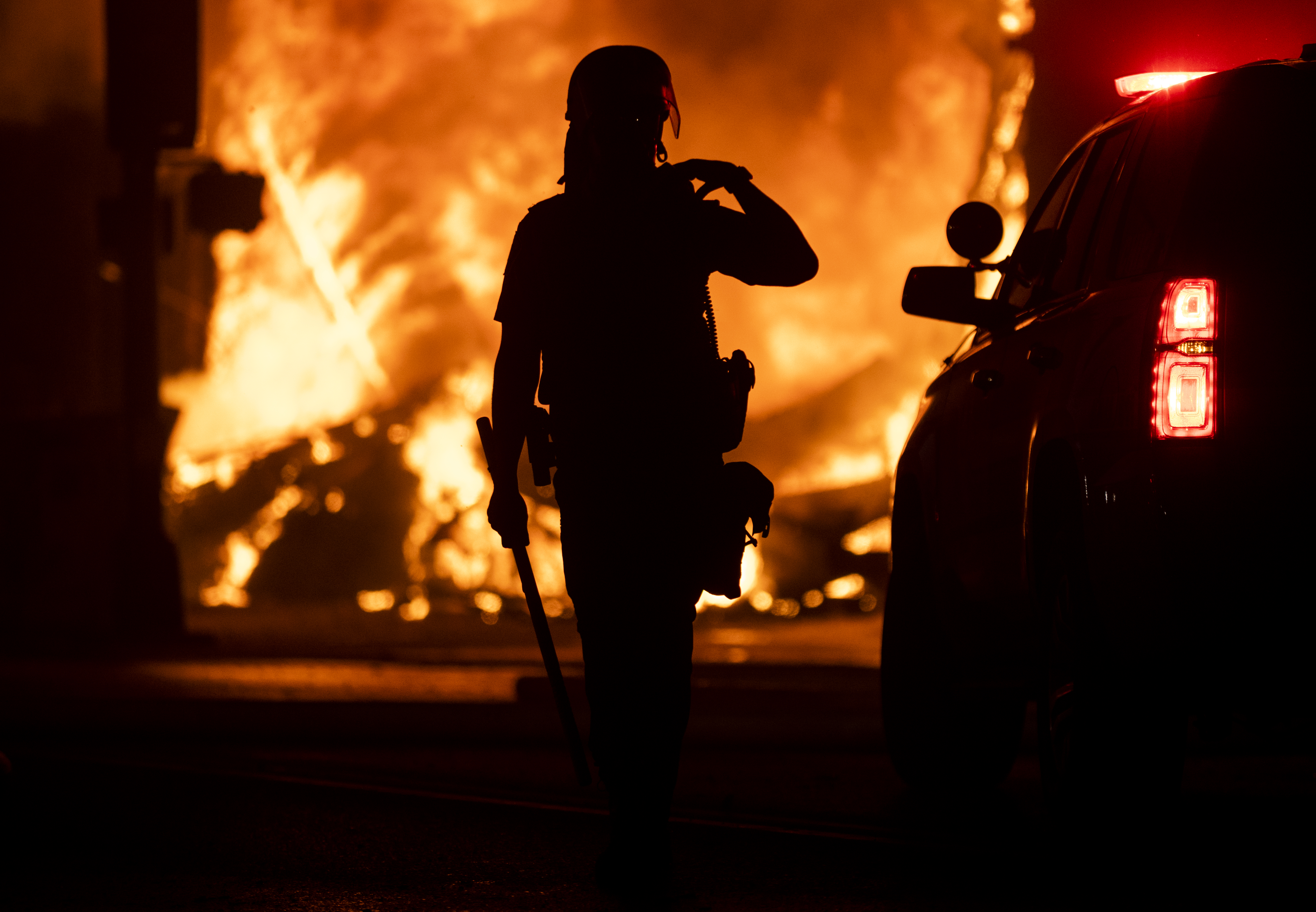 A police officer stands watch as a looted pawn shop burns behind them on May 28, 2020 in Minneapolis, Minnesota. (Photo by Stephen Maturen/Getty Images)