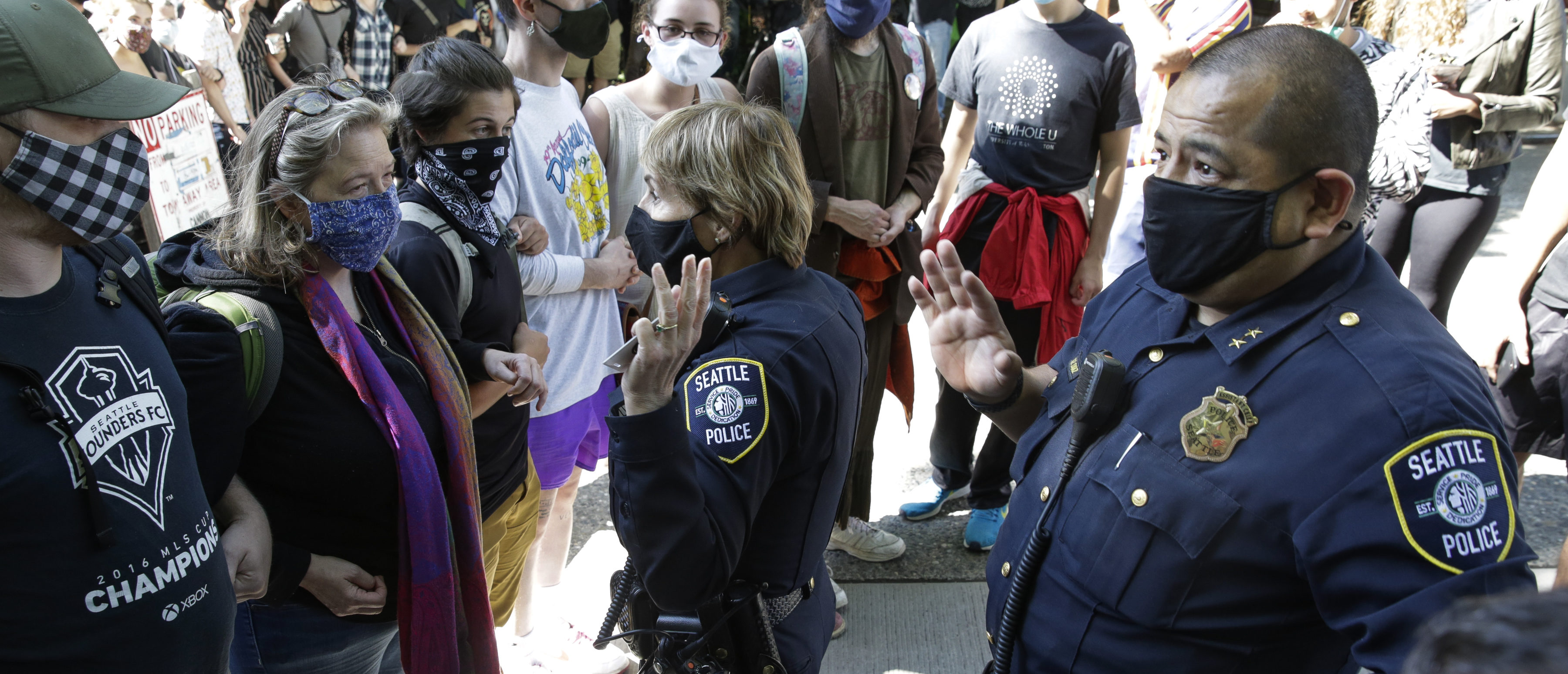 TOPSHOT - Seattle Police Assistant Chief Deanna Nollette and Assistant Chief Adrian Diaz are blocked by protesters from entering the newly created Capitol Hill Autonomous Zone (CHAZ) in Seattle, Washington on June 11, 2020. - Two police officers attempt to enter the area, but are blocked by people standing close together and holding cameras as they film. The area surrounding the East Precinct building has come to be known as the CHAZ, Capitol Hill Autonomous Zone. (JASON REDMOND/AFP via Getty Images)