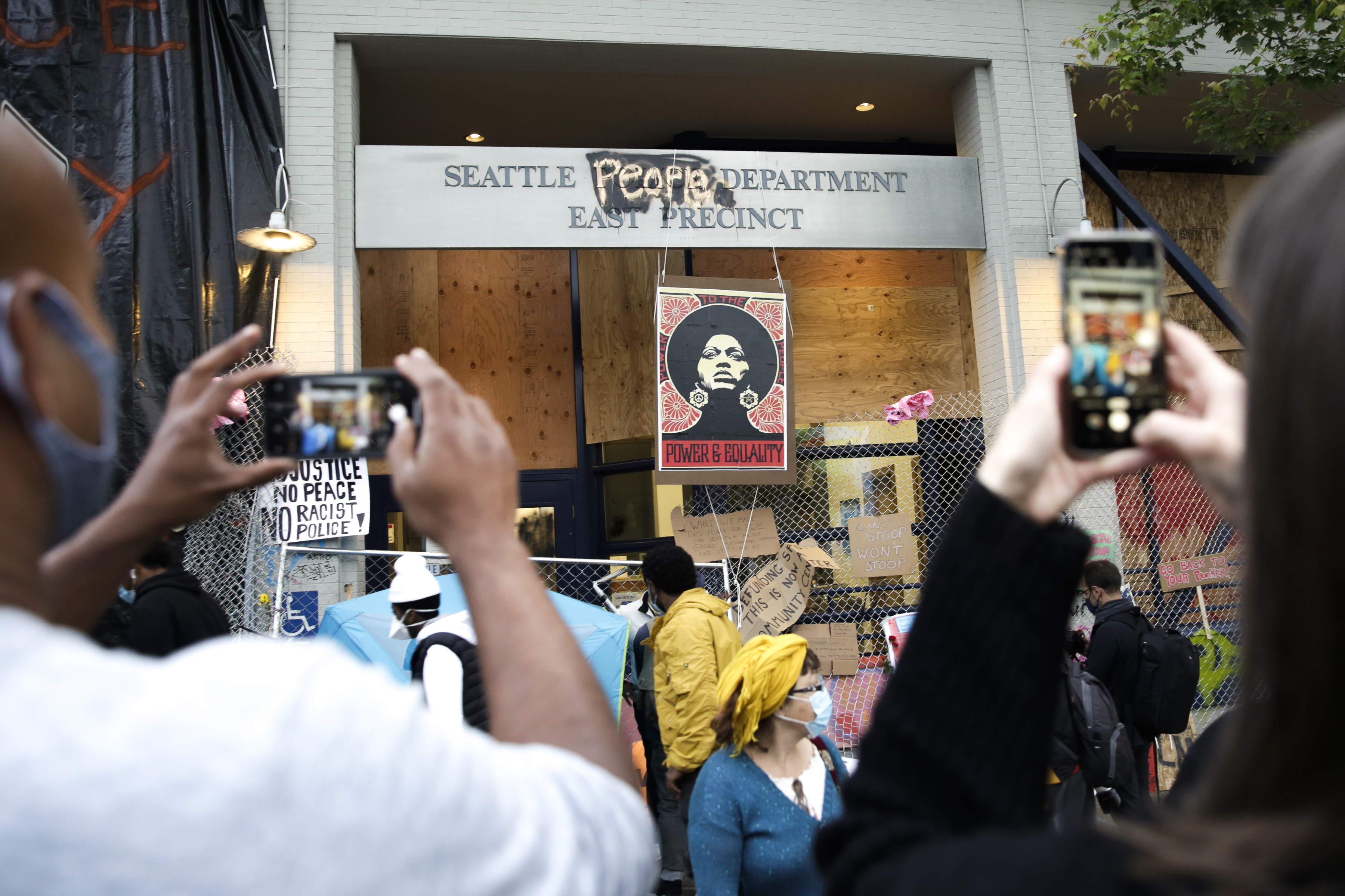 People photograph an image of activist Angela Davis displayed above the entrance to the Seattle Police Department's East Precinct, vacated June 8, and now surrounded by streets reopened to pedestrians forming an area named the Capitol Hill Autonomous Zone (CHAZ) in Seattle, Washington on June 12, 2020. (Photo: Jason Redmond/AFP via Getty Images)