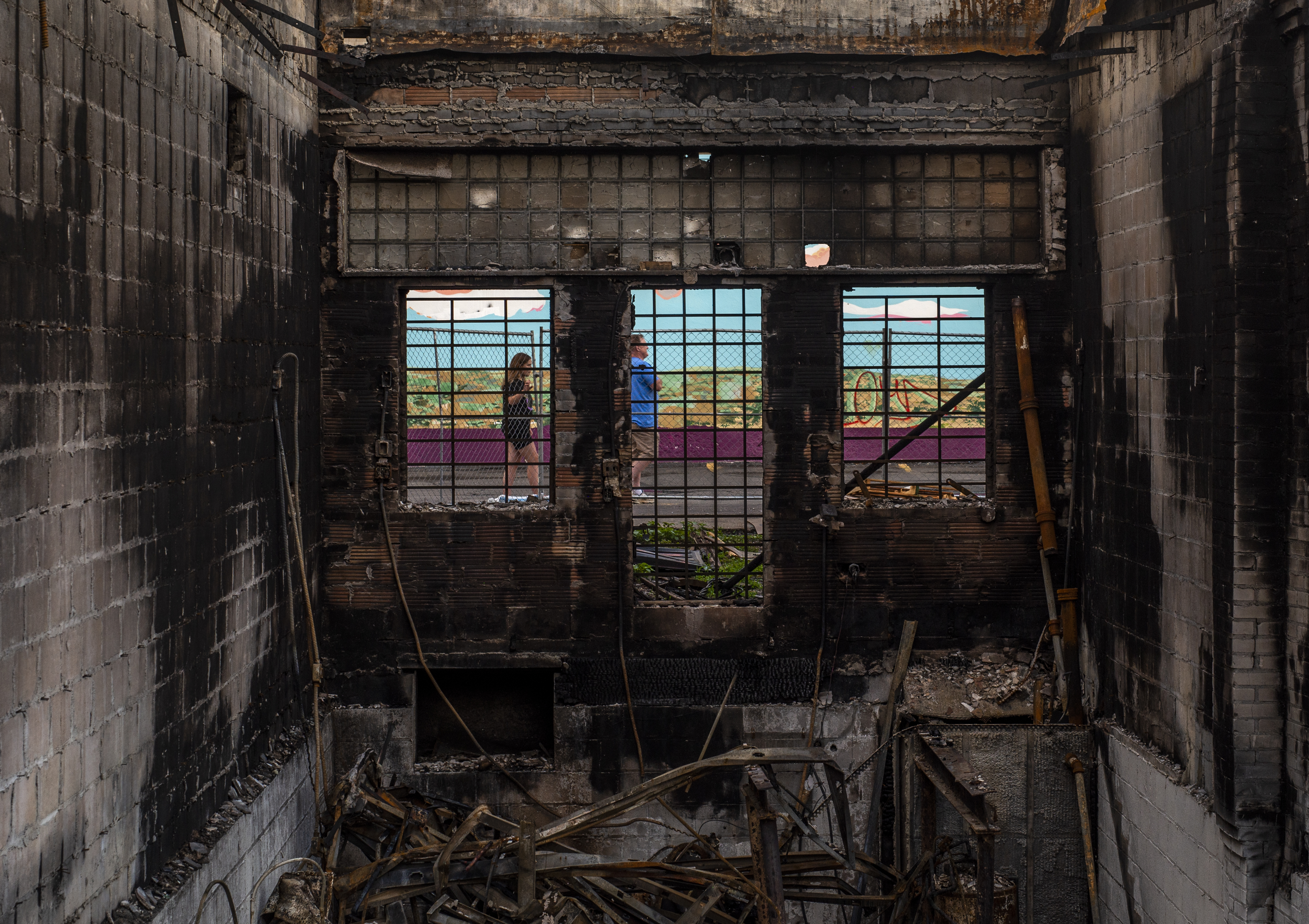 MINNEAPOLIS, MN - JUNE 21: People walk behind a destroyed tobacco store near the Third Police Precinct Station on June 21, 2020 in Minneapolis, Minnesota. (Photo by Stephen Maturen/Getty Images)