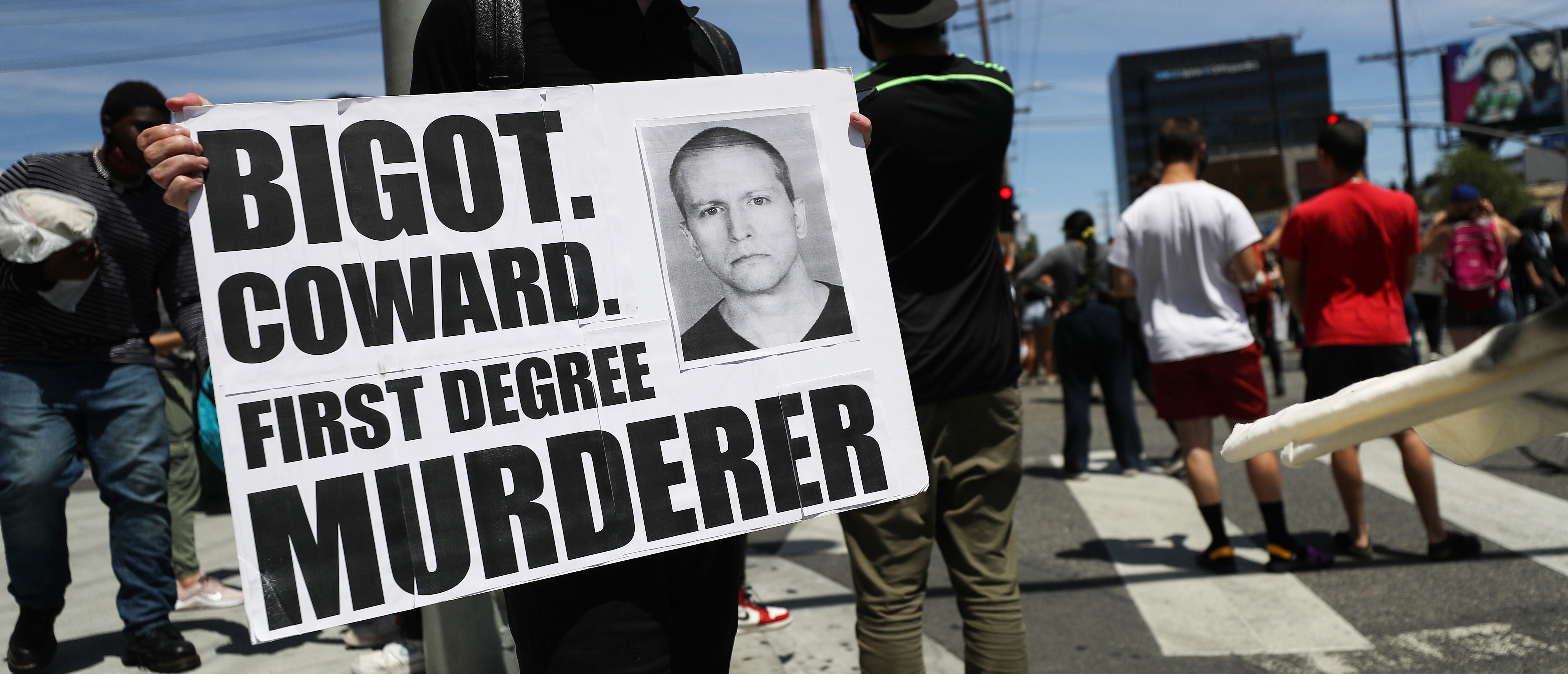 LOS ANGELES, CALIFORNIA - MAY 30: A protester holds a sign with a photo of former Minneapolis police officer Derek Chauvin during demonstrations following the death of George Floyd on May 30, 2020 in Los Angeles, California. Chauvin was taken into custody for Floyd's death. Chauvin has been accused of kneeling on Floyd's neck as he pleaded with him about not being able to breathe. Floyd was pronounced dead a short while later. Chauvin and 3 other officers, who were involved in the arrest, were fired from the police department after a video of the arrest was circulated. (Photo by Mario Tama/Getty Images)