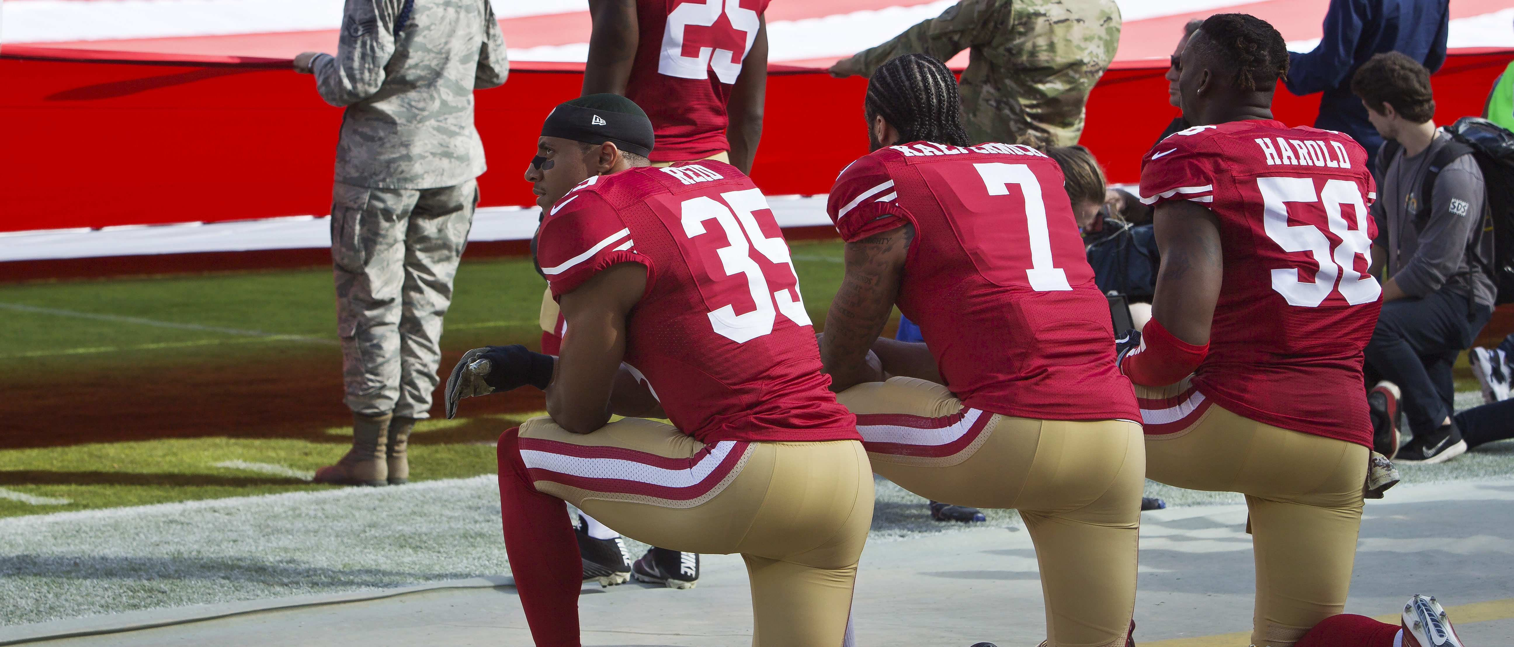 SANTA CLARA, CA - NOVEMBER 6: Quarterback Colin Kaepernick #7, safety Eric Reid #35, and linebacker Eli Harold #58 of the San Francisco 49ers kneel before a game against the New Orleans Saints with the U.S. flag unfurled in honor of the armed services on November, 6 2016 at Levi's Stadium in Santa Clara, California. The Saints won 41-23. (Photo by Brian Bahr/Getty Images)