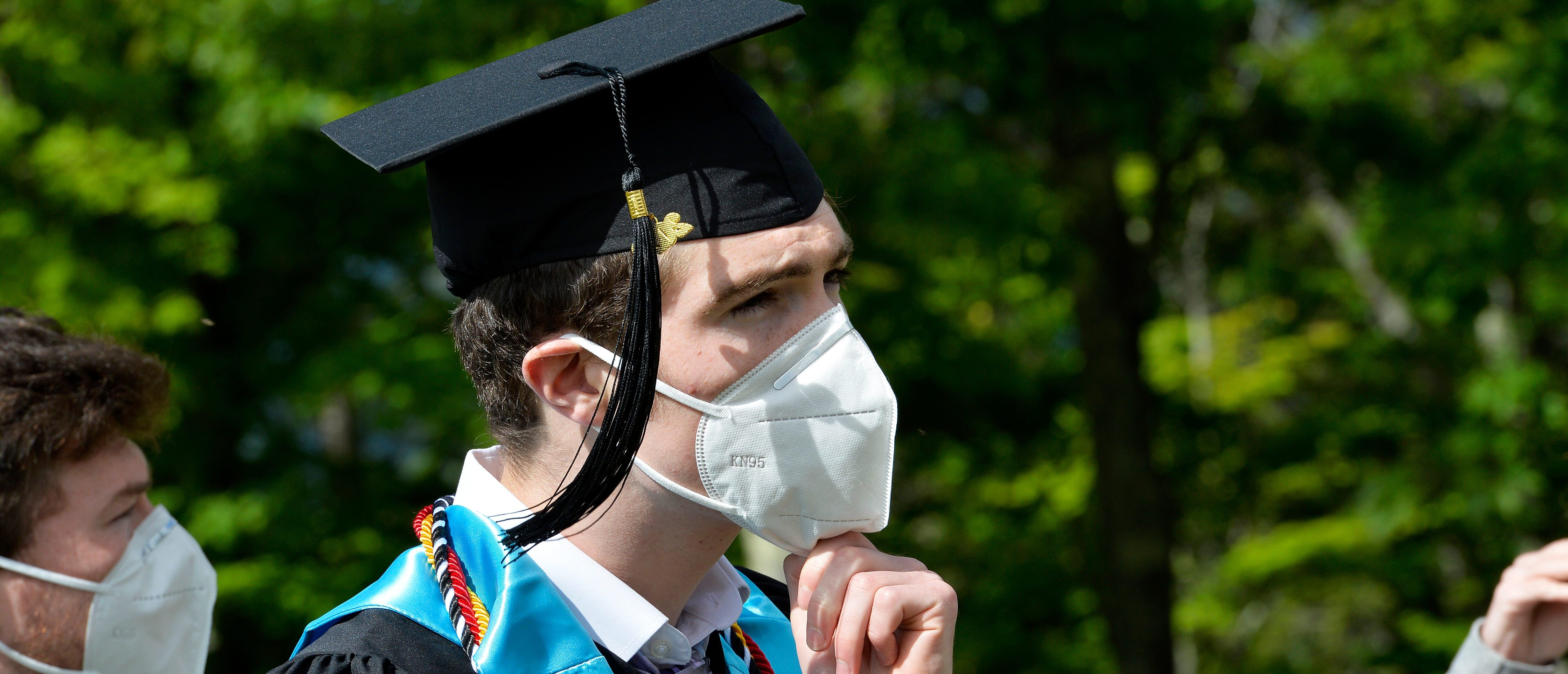 A student puts his mask back on after taking family photos during the Kenneth High School Class of 2020 Commencement Exercises at Cranmore Mountain in North Conway, New Hampshire on June 13, 2020. - The unique graduation was a way to follow health guidelines for Covid-19 and allow the students to have their graduation day. (Photo by Joseph Prezioso / AFP) (Photo by JOSEPH PREZIOSO/AFP via Getty Images)