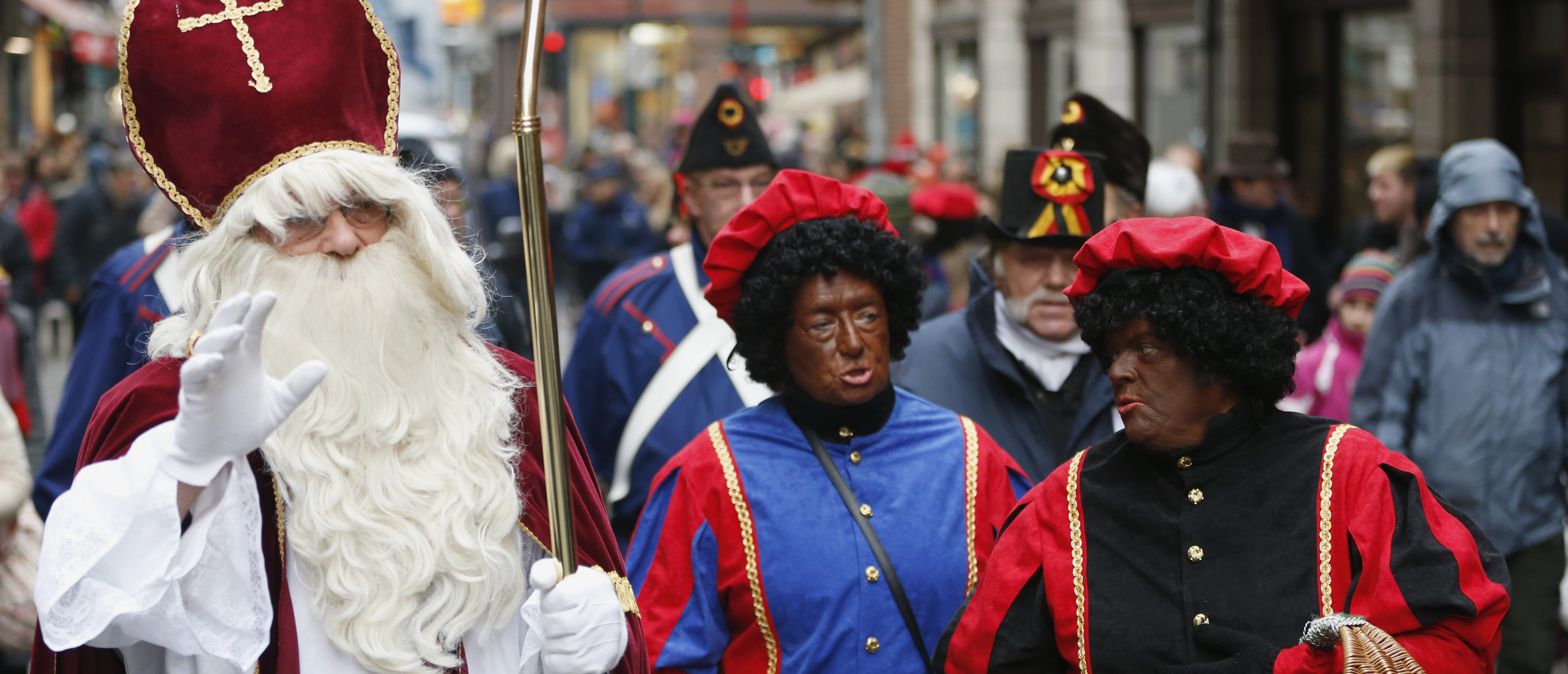 Saint Nicholas (L) is followed by his two assistants called "Zwarte Piet" (Black Pete) during a traditional parade in central Brussels December 1, 2012. The Netherlands and Belgium are two countries that pride themselves on progressive laws and open societies, but critics say they are stuck in the dark ages when it comes to depictions of Santa Claus and his helpers. Saint Nicholas, or "Sinterklaas" in Dutch, brings presents to children on December 5 in the Netherlands and on December 6 in Belgium, and is always accompanied by at least one assistant dressed in 17th century costume who has a blackened face. Picture taken December 1, 2012. REUTERS/Francois Lenoir (BELGIUM - Tags: ENTERTAINMENT RELIGION SOCIETY) - GM1E8C31KJF01
