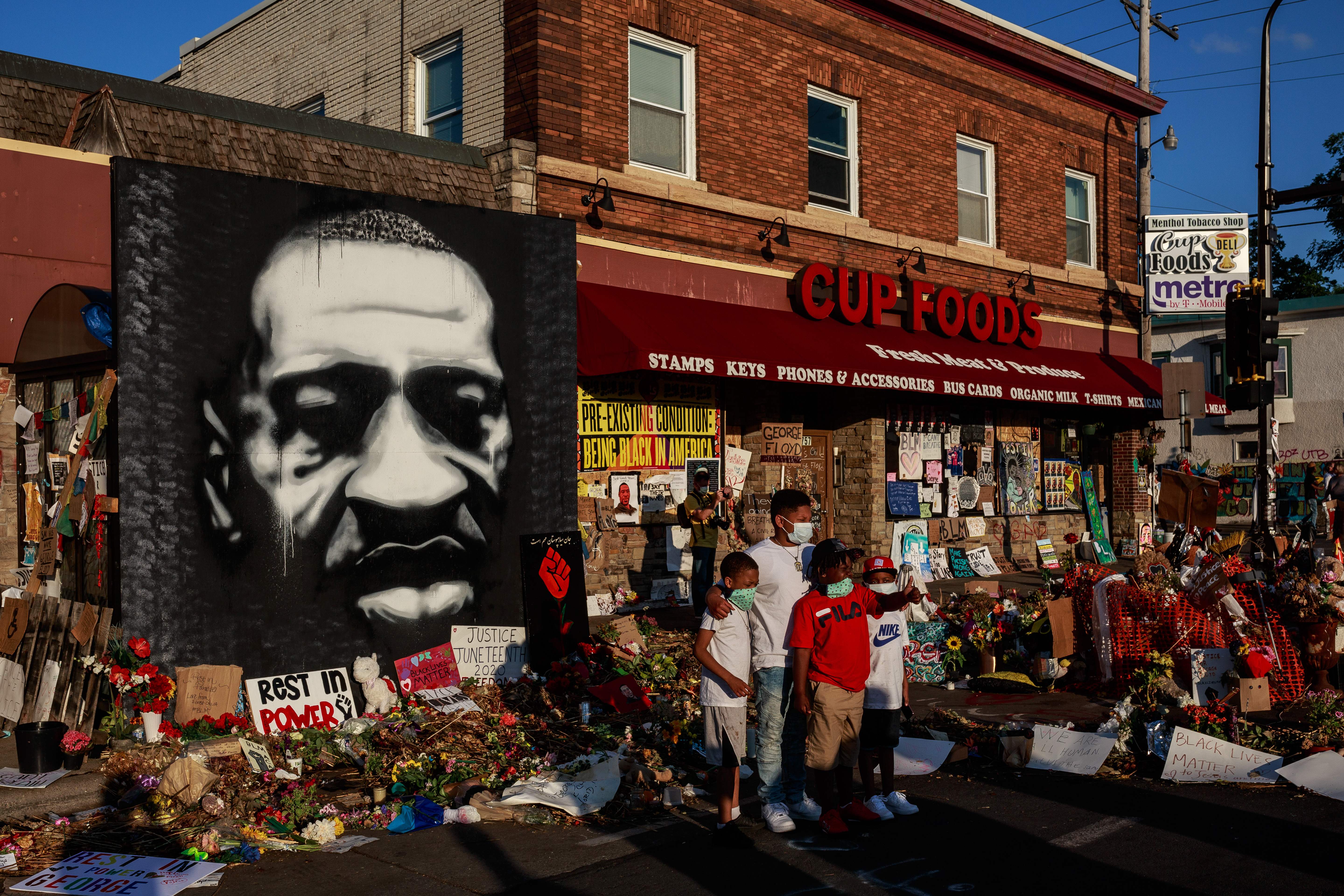Kids pose as their father takes a photo in front of a makeshift memorial to George Floyd near the site where he died in police custody, in Minneapolis, Minnesota on June 20, 2020. (KEREM YUCEL/AFP via Getty Images)
