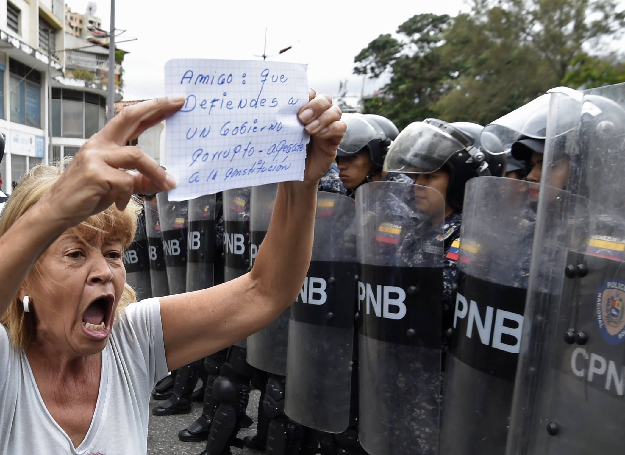 A woman demonstrates with a sign reading "Friend: you who defend a corrupt government, get attached to the constitution", in front of a line of riot police outside the Venezuelan Navy command headquarters at San Bernardino neighborhood in Caracas on May 4, 2019. - Venezuelan President Nicolas Maduro called on the armed forces to be "ready" in the event of a US military offensive against the South American country, in a speech to troops on Saturday. His speech at a military base came as opposition leader Juan Guaido rallied his supporters in a new day of protests to press the armed forces to support his bid to dislodge Maduro. (JUAN BARRETO/AFP via Getty Images)