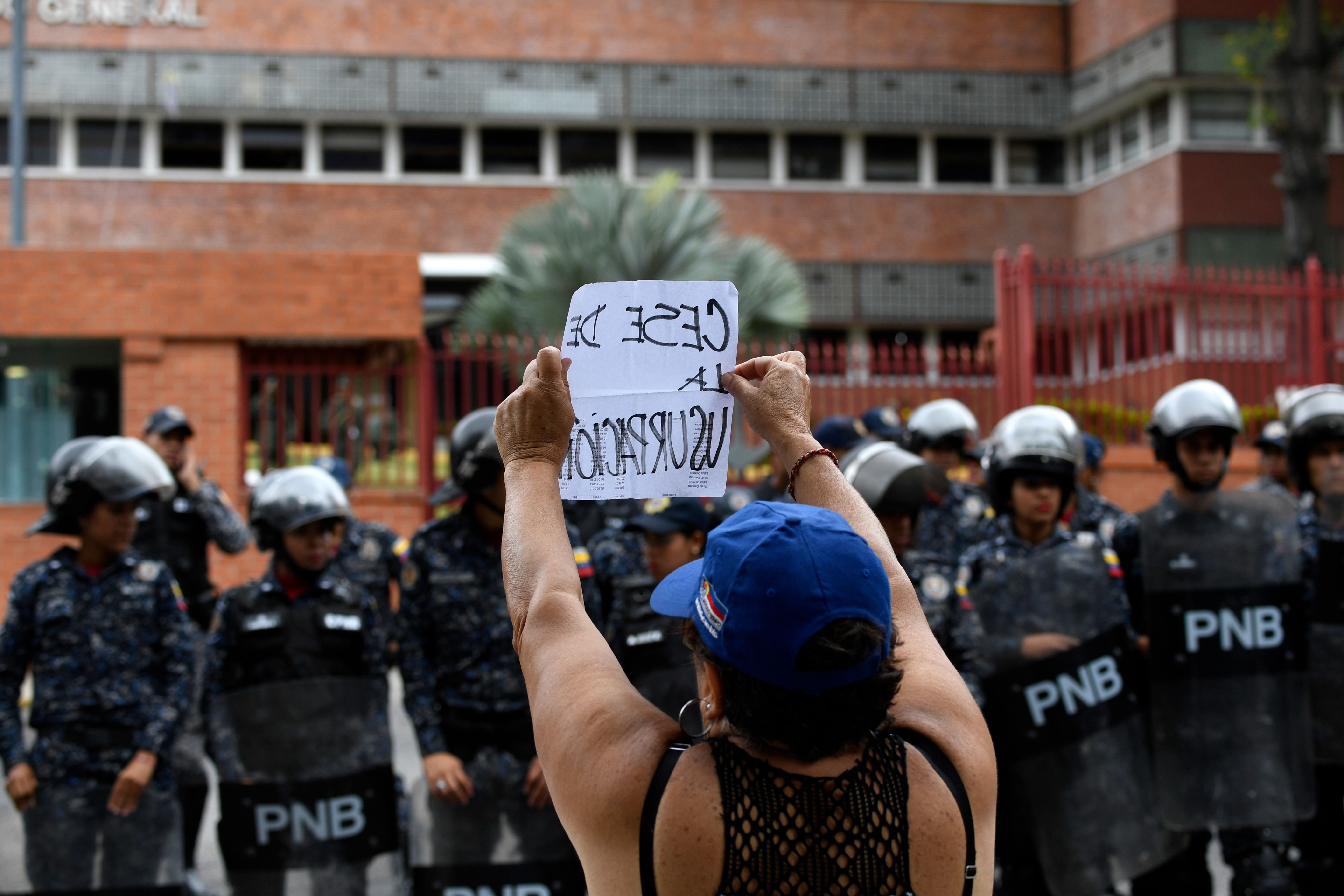 A woman demonstrates with a sign reading "End of usurpation", in front of a line of riot police outside the Venezuelan Navy command headquarters at San Bernardino neighborhood in Caracas on May 4, 2019. - Venezuelan President Nicolas Maduro called on the armed forces to be "ready" in the event of a US military offensive against the South American country, in a speech to troops on Saturday. His speech at a military base came as opposition leader Juan Guaido rallied his supporters in a new day of protests to press the armed forces to support his bid to dislodge Maduro. (JUAN BARRETO/AFP via Getty Images)