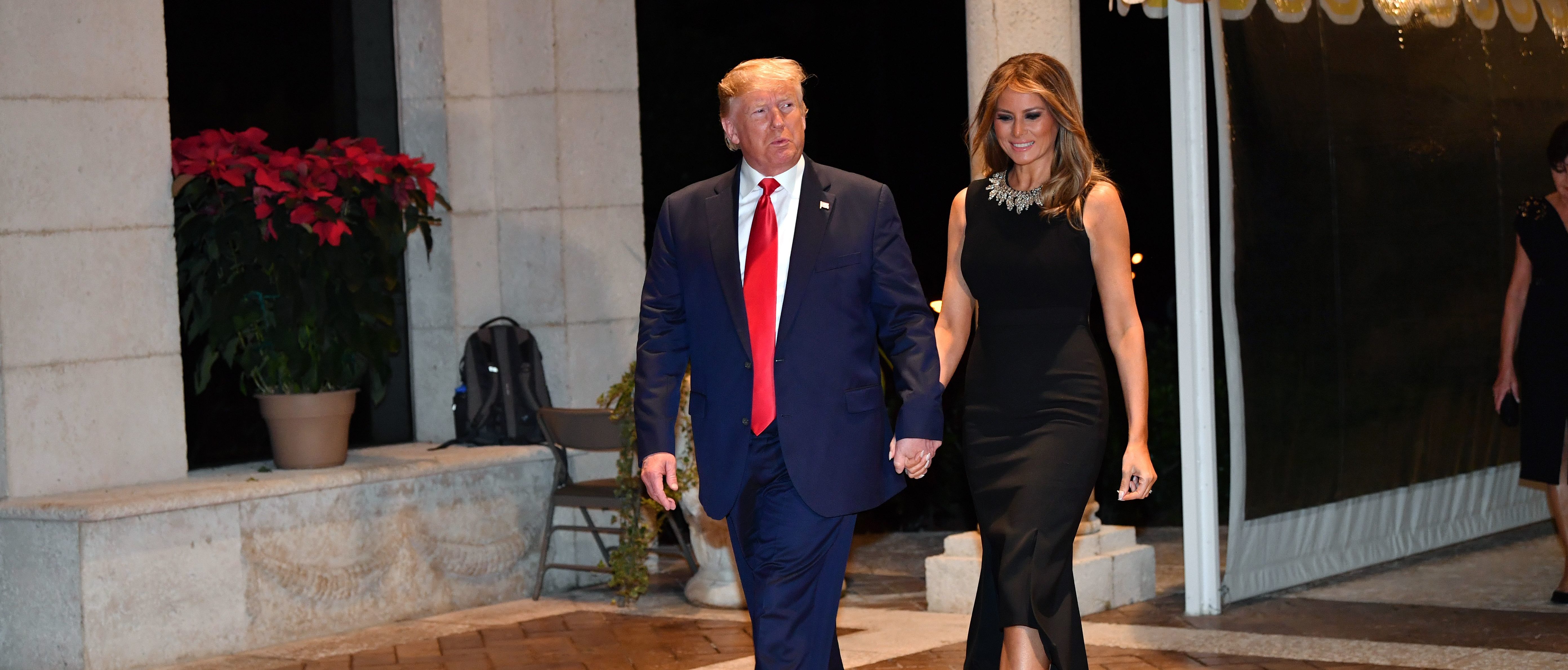 US President Donald Trump and First Lady Melania Trump arrive for a Christmas Eve dinner with his family at Mar-A-Lago in Palm Beach, Florida on Dec. 24, 2019. (Photo by NICHOLAS KAMM/AFP via Getty Images)