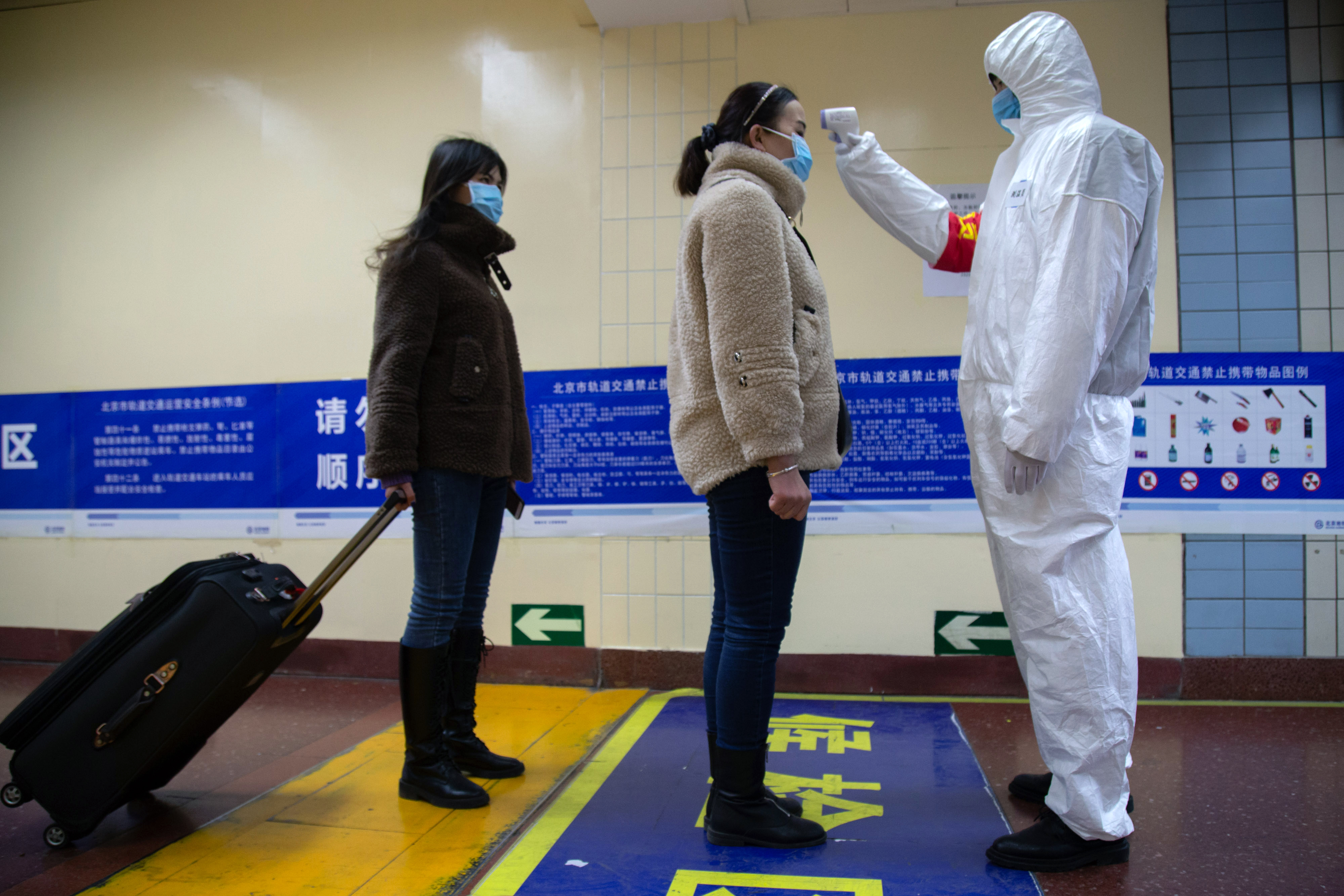 BEIJING, CHINA - JANUARY 26: A health worker checks the temperature of women entering the subway on January 26, 2020 in Beijing, China. The number of cases of coronavirus rose to 1,975 in mainland China on Sunday. Authorities tightened restrictions on travel and tourism this weekend after putting Wuhan, the capital of Hubei province, under quarantine on Thursday. The spread of the virus corresponds with the first days of the Spring Festival, which is one of the biggest domestic travel weeks of the year in China. Popular tourism landmarks in Beijing including the Forbidden City, Badaling Great Wall, and The Palace Museum were closed to the public starting Saturday. The Beijing Municipal Education Commission announced it will delay reopening schools from kindergarten to university. The death toll on Sunday rose to 56. The majority of fatalities are in Wuhan where the first cases of the virus were reported last month.(Photo by Betsy Joles/Getty Images)
