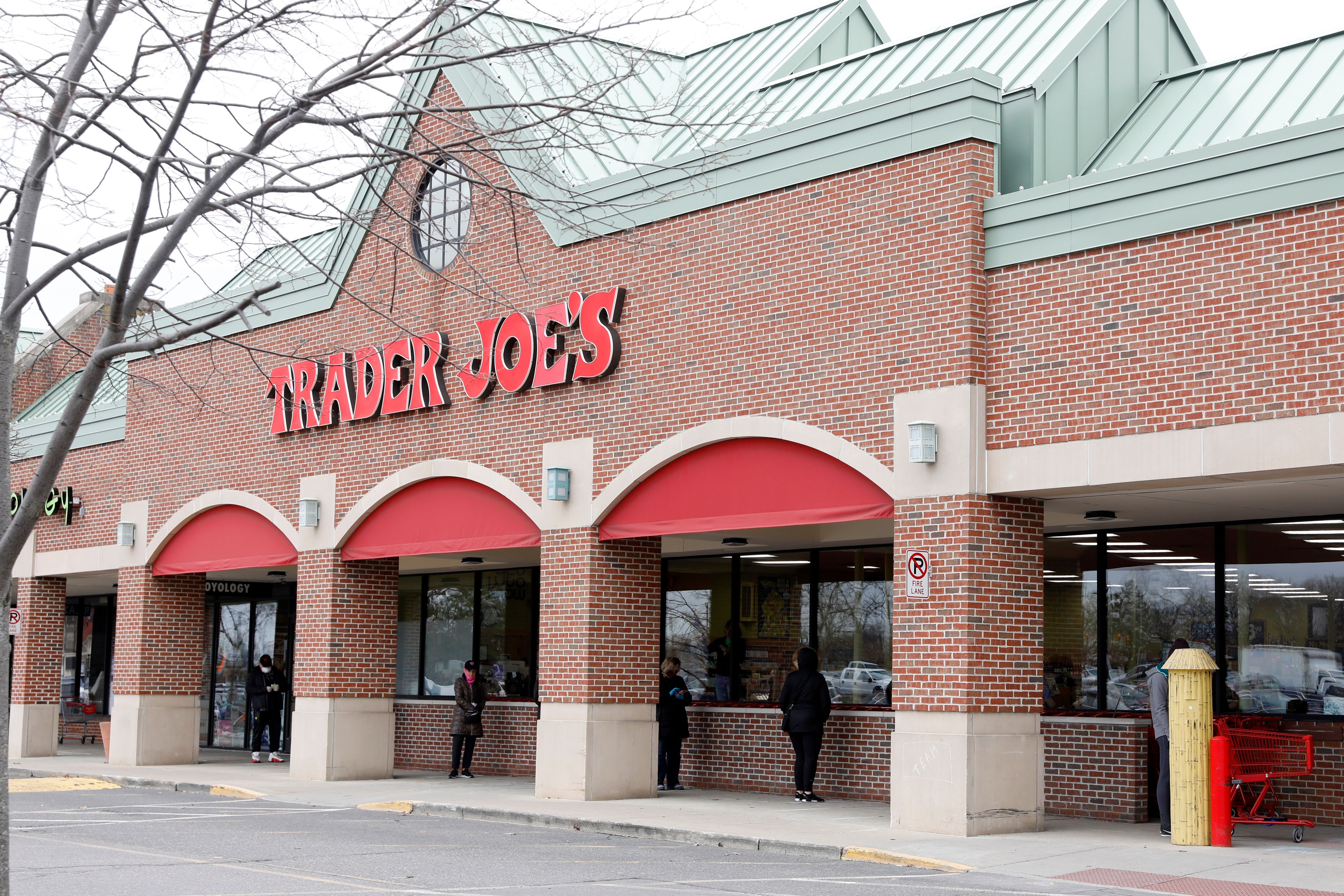 People social distance as they wait to get into the Trader Joe's store to avoid the spread of COVID-19 in Bloomfield Hills Michigan on March 30, 2020. - Trader Joe's only lets 20 customers in the store at a time to shop. (Photo by JEFF KOWALSKY / AFP) (Photo by JEFF KOWALSKY/AFP via Getty Images)