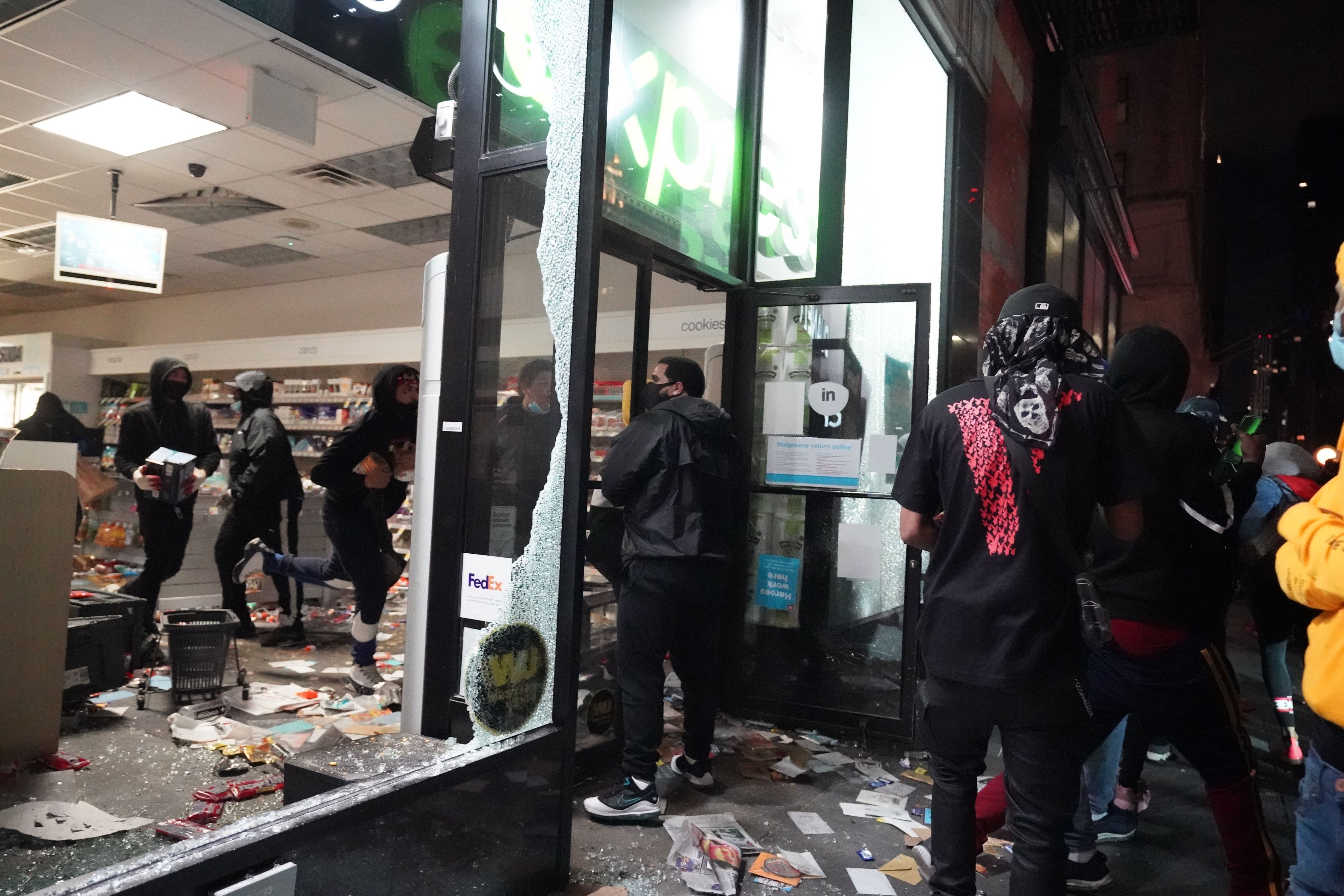 TOPSHOT - People loot a store during demonstrations over the death of George Floyd by a Minneapolis police officer on June 1, 2020 in New York. - New York's mayor Bill de Blasio today declared a city curfew from 11:00 pm to 5:00 am, as sometimes violent anti-racism protests roil communities nationwide. Saying that "we support peaceful protest," De Blasio tweeted he had made the decision in consultation with the state's governor Andrew Cuomo, following the lead of many large US cities that instituted curfews in a bid to clamp down on violence and looting. (Photo by Bryan R. Smith / AFP) (Photo by BRYAN R. SMITH/AFP via Getty Images)