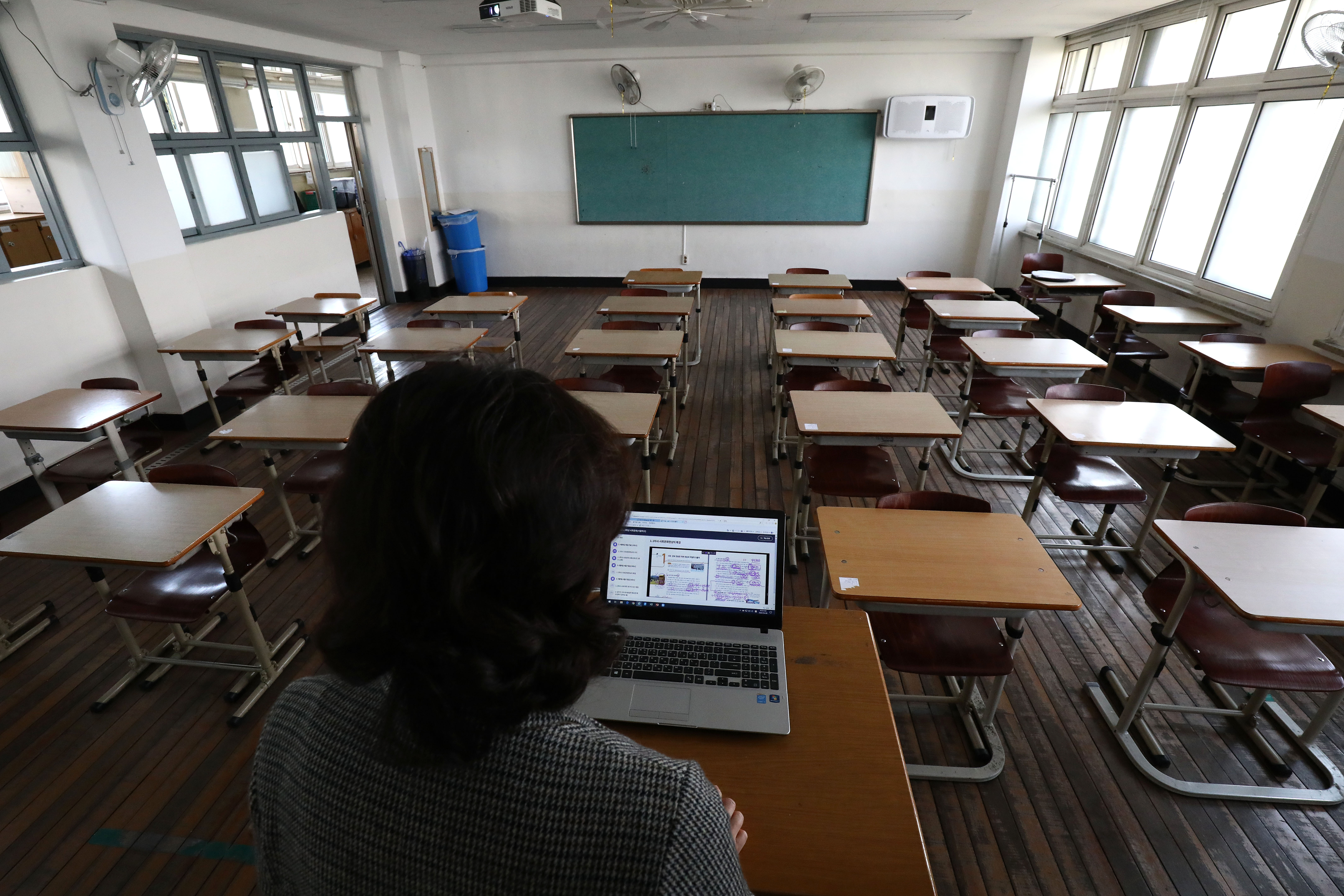A teacher wears a mask as she gives a lesson on the first day of online class in an empty classroom as South Koreans take measures to protect themselves against the spread of coronavirus (COVID-19) at Seoul Girls High School on April 09, 2020 in Seoul, South Korea. South Korea started the new school year in stages from today, beginning with online classes for middle and high school senior students. South Korea has called for expanded public participation in social distancing, as the country witnesses a wave of community spread and imported infections leading to a resurgence in new cases of COVID-19. According to the Korea Center for Disease Control and Prevention, 39 new cases were reported. The total number of infections in the nation tallies at 10,423. (Photo by Chung Sung-Jun/Getty Images)