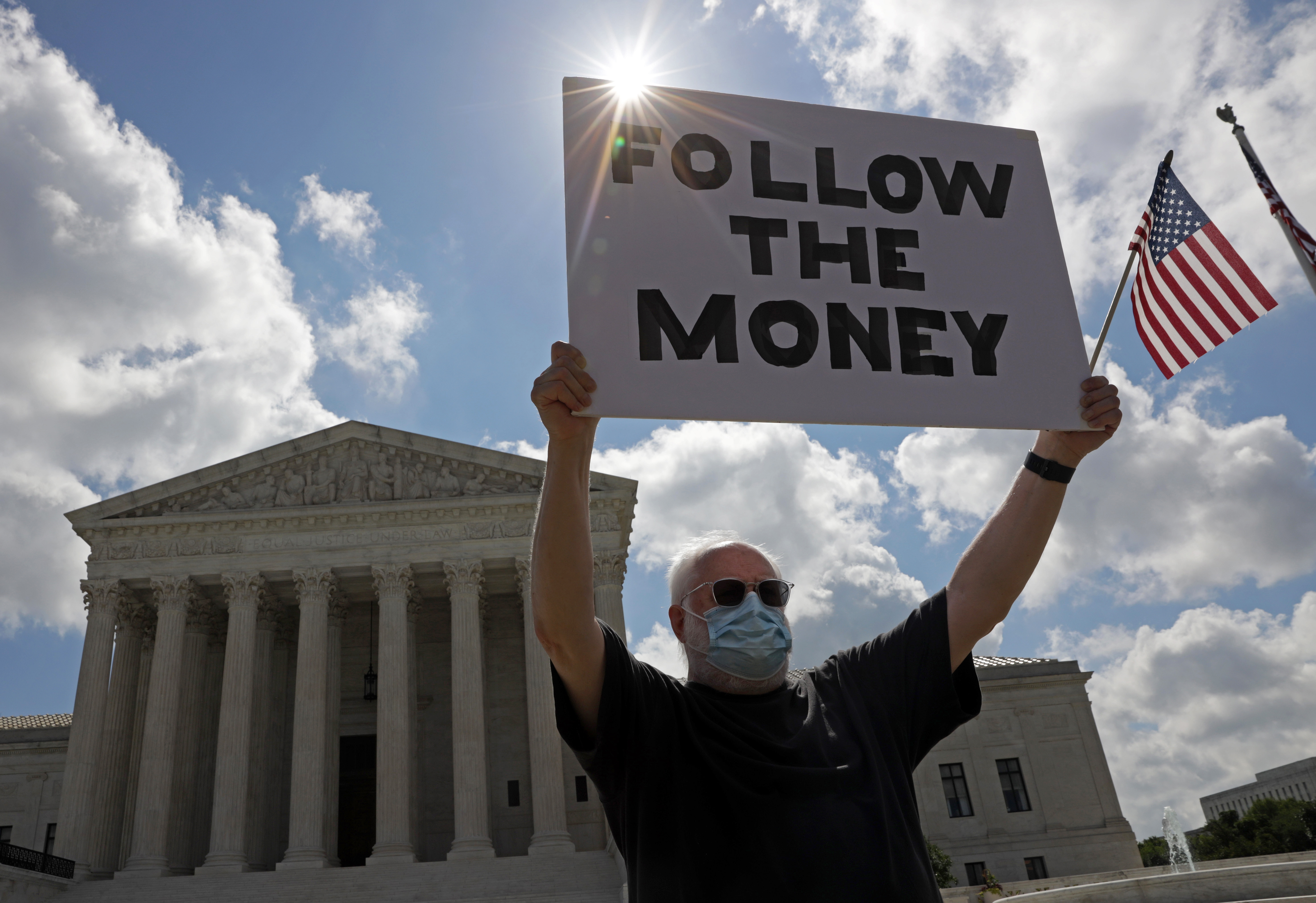 WASHINGTON, DC - JULY 09: A man holds up a “Follow the Money” sign in front of the U.S. Supreme Court July 9, 2020 in Washington, DC. The Supreme Court has issued a 7-2 ruling that New York prosecutor can obtain President Donald Trump’s financial records, including tax returns. (Photo by Alex Wong/Getty Images)