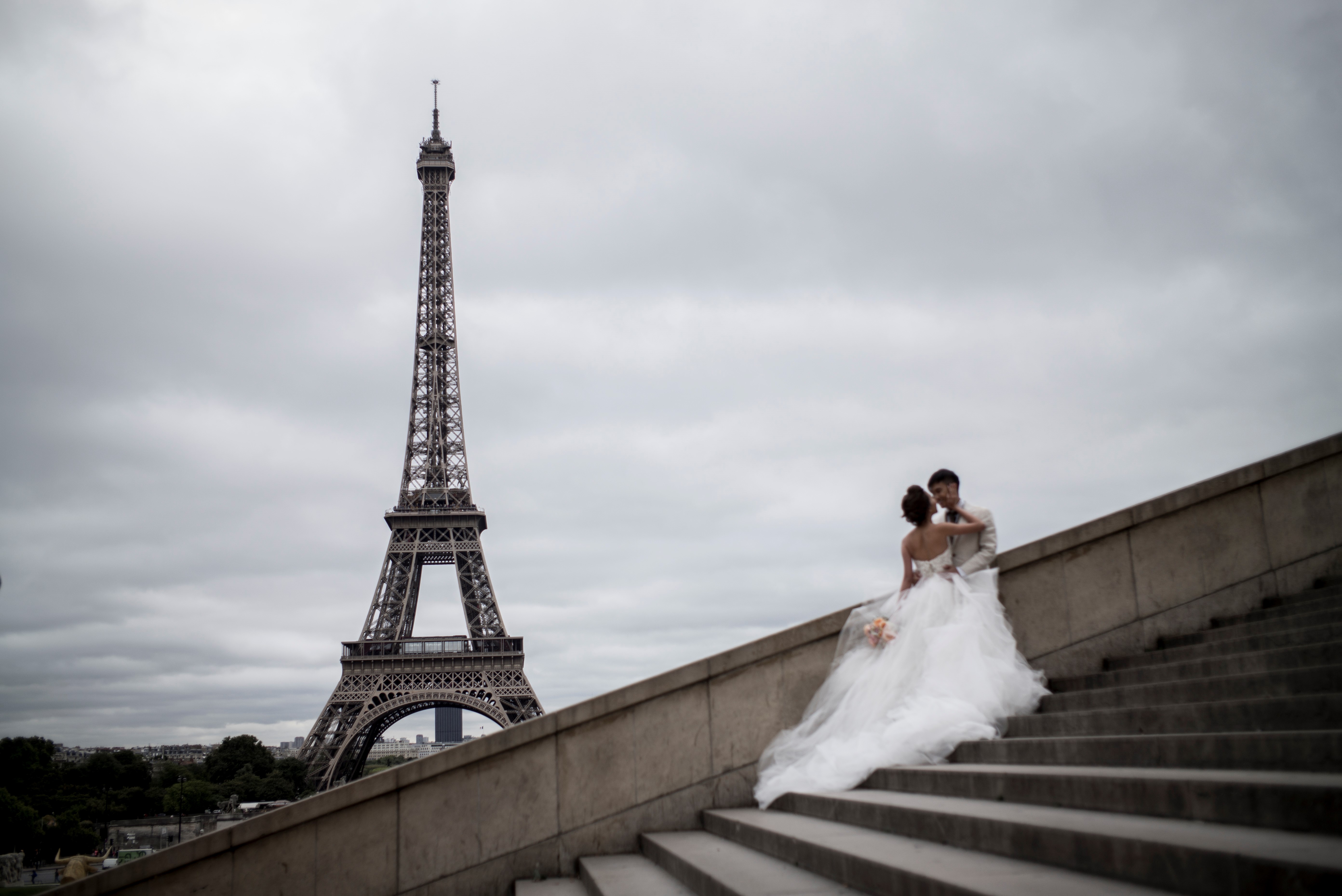 A young married couple kisses in front of the Eiffel Tower in Paris on September 29, 2016. (PHILIPPE LOPEZ/AFP via Getty Images)
