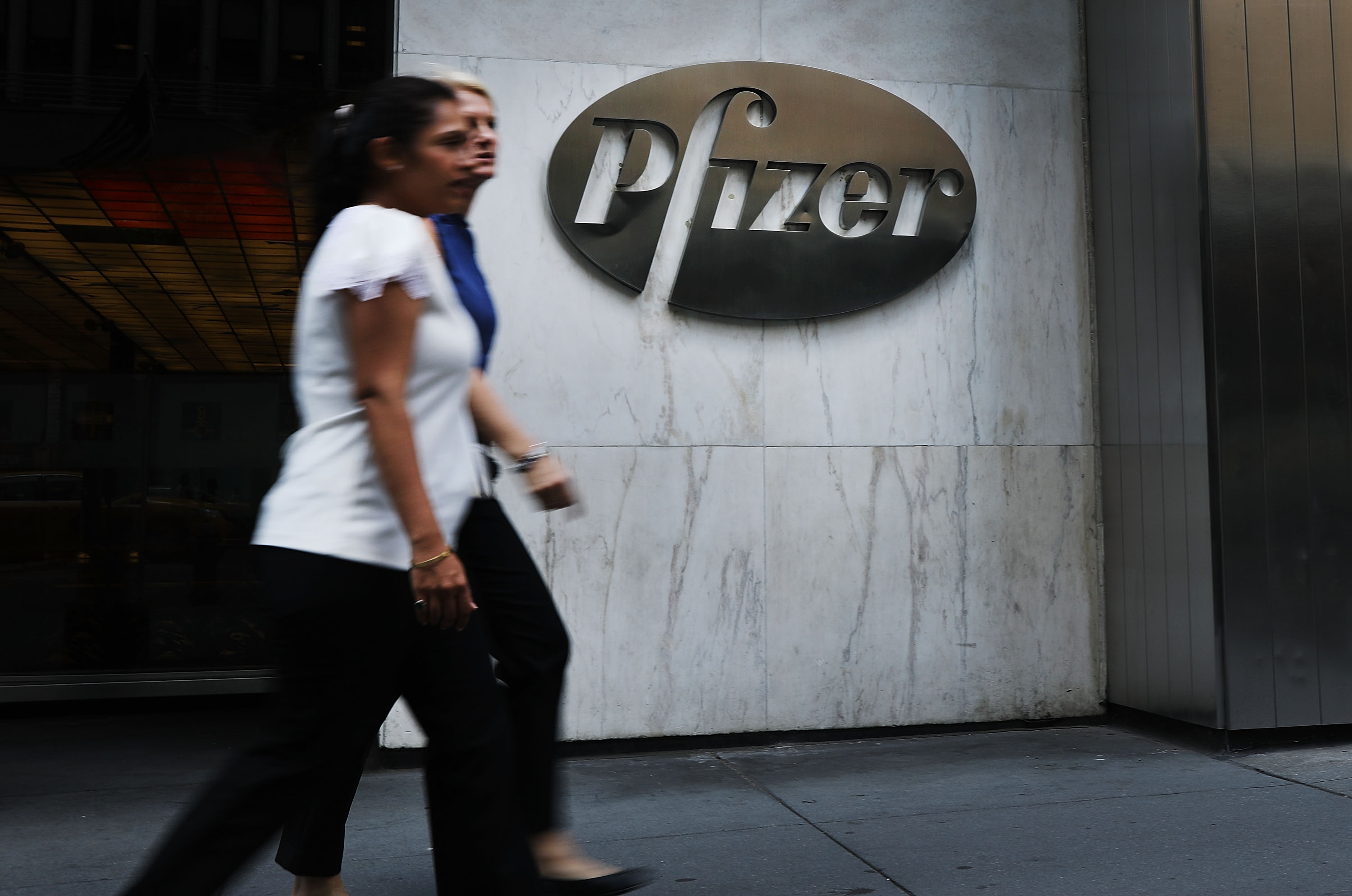 People walk by the Pfizer headquarters in New York City. (Photo: Spencer Platt/Getty Images)