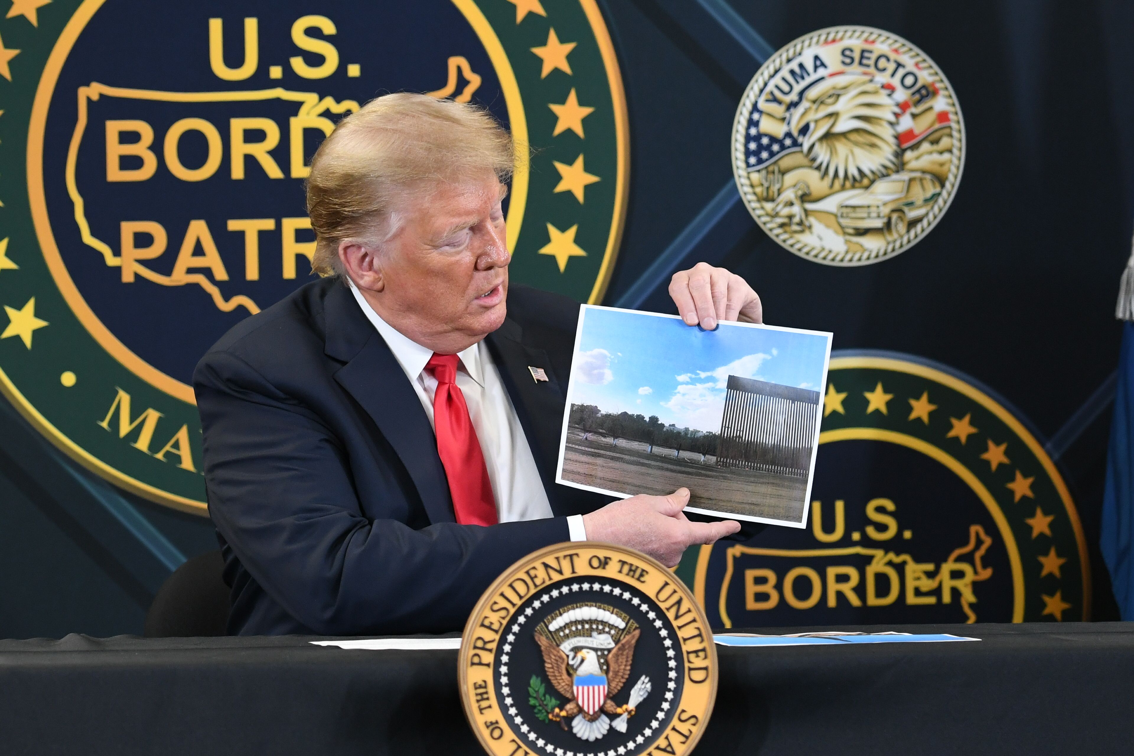 US President Donald Trump shows a photo of the border wall upon arrival at the US Border Patrol station in Yuma, Arizona, June 23, 2020, as he travels to visit the border wall with Mexico. (Photo by SAUL LOEB / AFP)