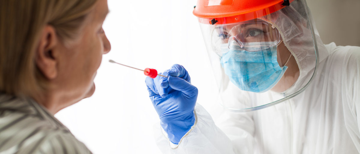 Physician wearing personal protective equipment performing a Coronavirus COVID-19 PCR test, patient nasal NP and oral OP swab sample specimen collection process, viral RT-PCR DNA diagnostic procedure [Shutterstock/Cryptographer]