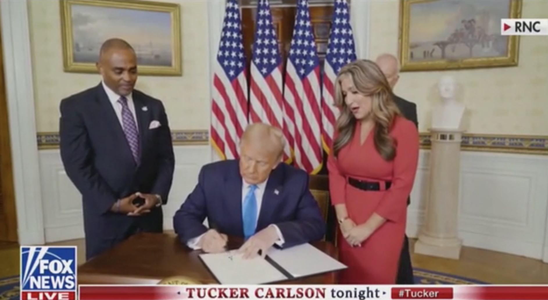 Hope for Prisoners founder Jon Ponder (R) watches as President Donald Trump signs a Presidential Pardon for him during the Republican National Convention on “Tucker Carlson Live,” Aug. 25, 2020. Fox News screenshot