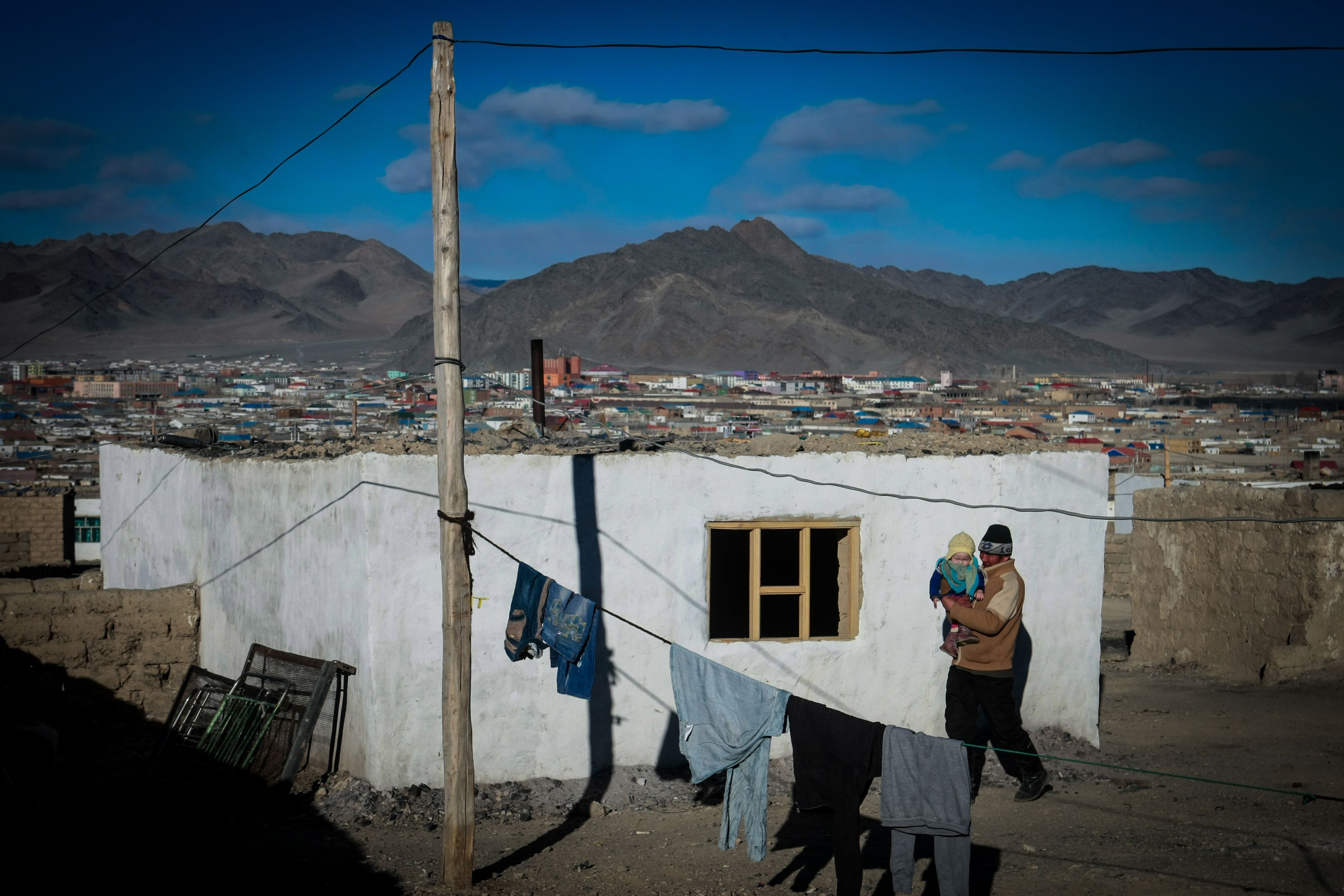 TOPSHOT - This photo taken on March 4, 2014 shows a man carrying a child in the center of Bayan-Ulgii, in Ulgii soum, in Mongolia. - (BYAMBASUREN BYAMBA-OCHIR/AFP via Getty Images)