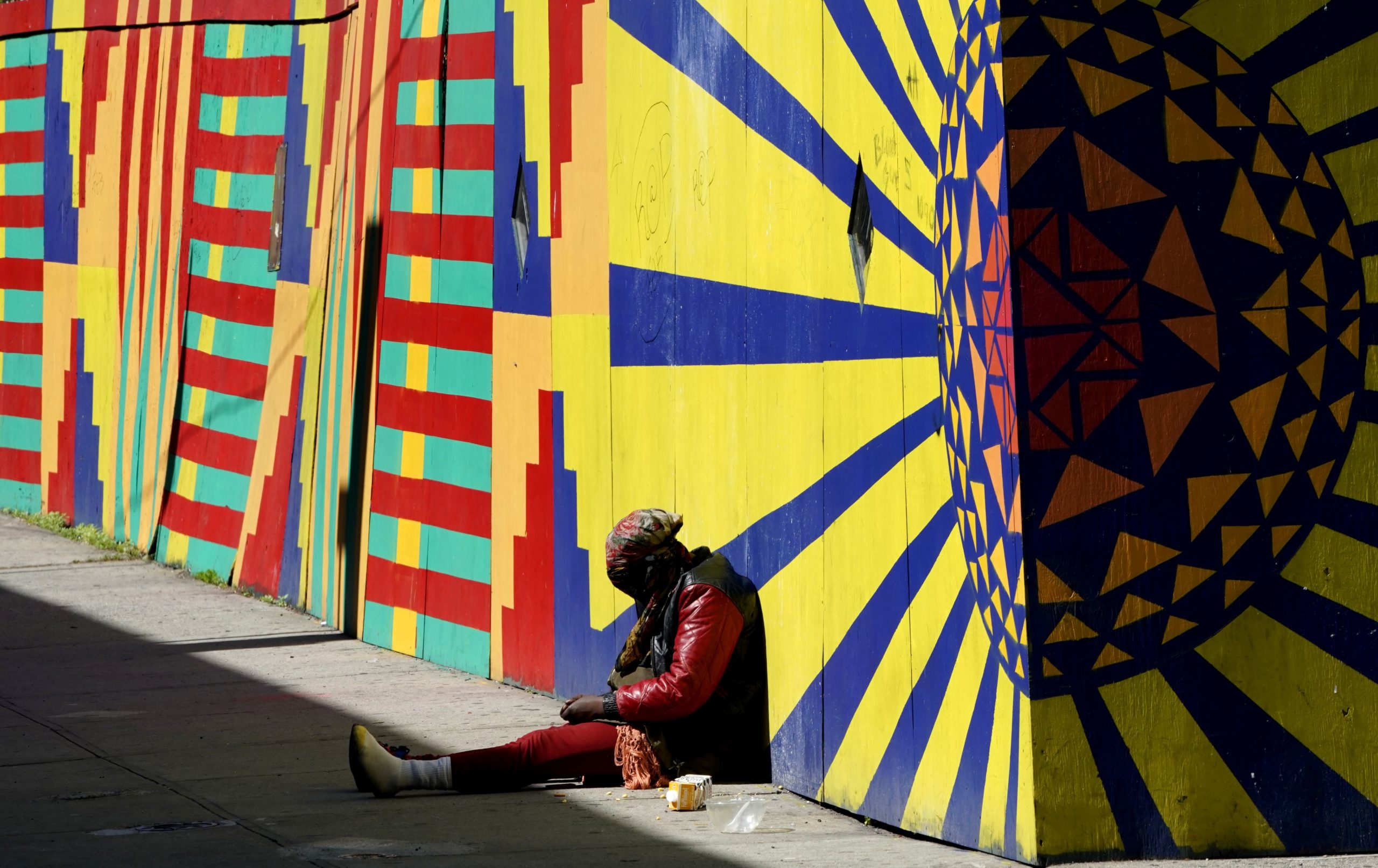 A woman sits on the sidewalk in the Harlem area of New York City on May 5, 2020, as the fear of exposure to COVID-19 in the city run shelters spreads. (Photo by Timothy A. Clary/AFP via Getty Images)