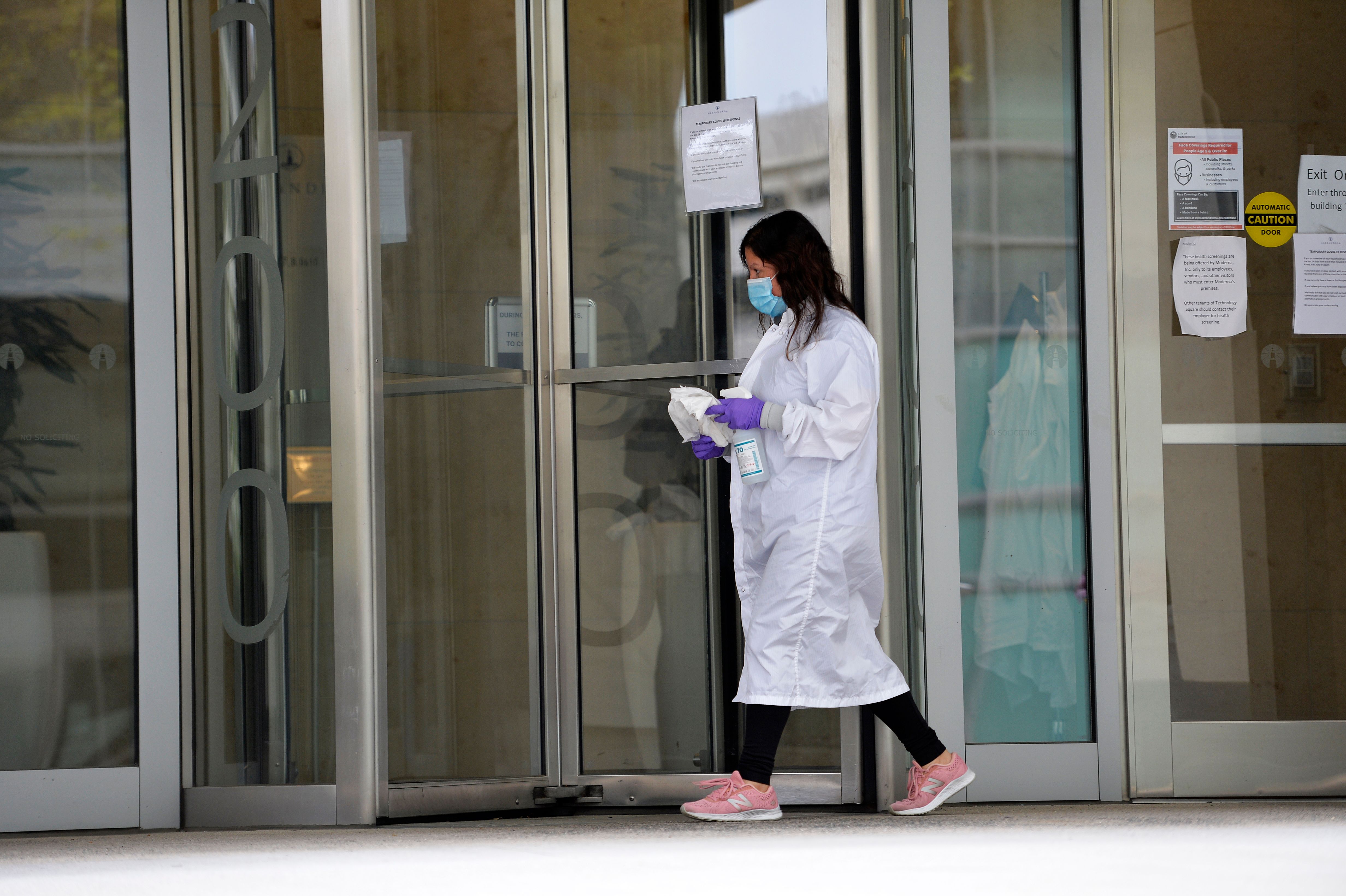 A women cleans the entrance doors to Moderna headquarters in Cambridge, Massachusetts on May 18, 2020. - US biotech firm Moderna reported promising early results from the first clinical tests of an experimental vaccine against the novel coronavirus performed on a small number of volunteers. The Cambridge, Massachusetts-based company said the vaccine candidate, mRNA-1273, appeared to produce an immune response in eight people who received it similar to that seen in people convalescing from the virus. (Photo by Joseph Prezioso / AFP) (Photo by JOSEPH PREZIOSO/AFP via Getty Images)