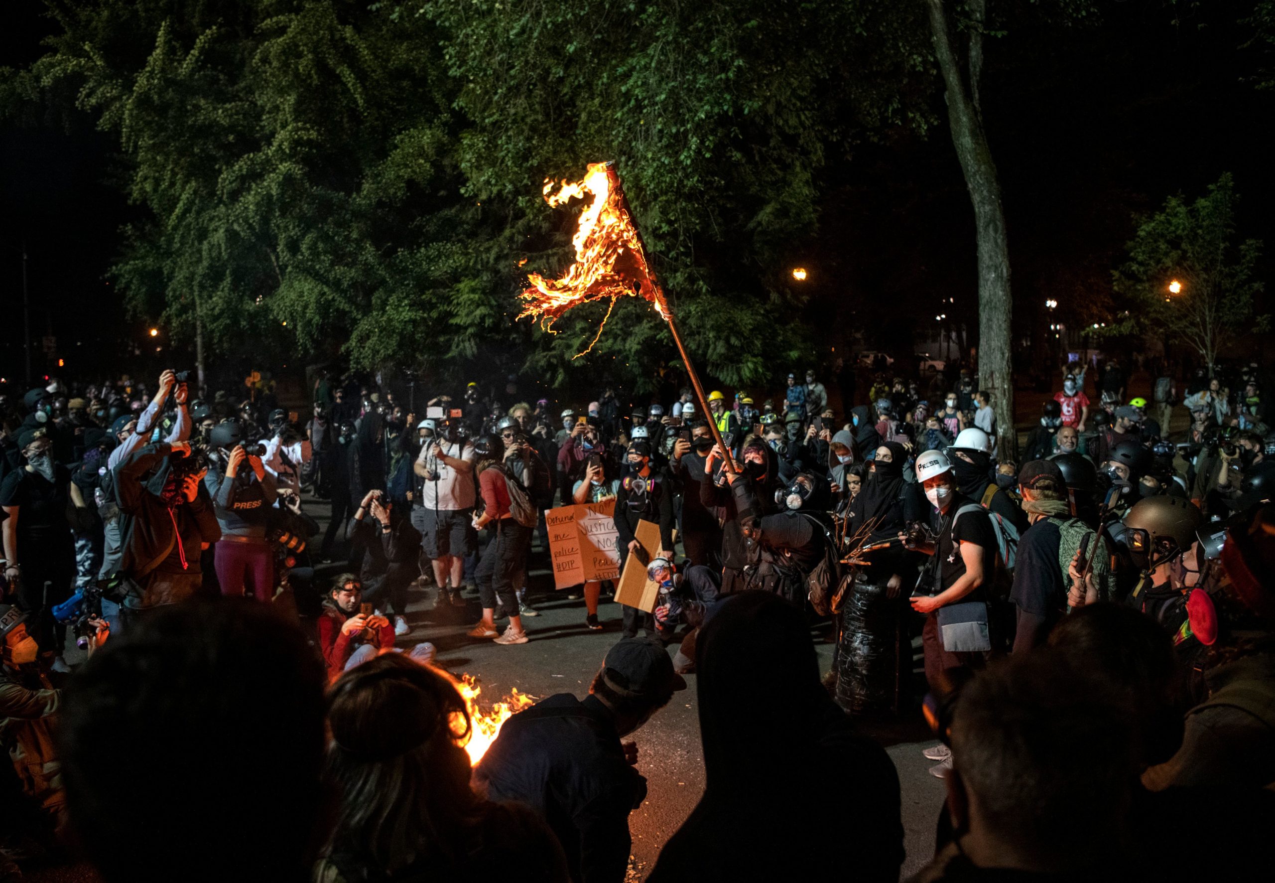 A demonstrator burns an American flag outside the Mark O. Hatfield United States Courthouse late Friday night during the protest on July 31, 2020 in Portland, Oregon. - US federal officers will stay in the protest-wracked city of Portland until local law enforcement officials finish a "cleanup of anarchists and agitators," the US President said. The forces -- whose deployment was seen by many as part of the president's law-and-order strategy for re-election and exacerbated tensions between authorities and anti-racism protestors -- had been scheduled to begin their phased pullout from Portland on July 30. Law enforcement did not engage with the demonstration on Friday night. (Photo by Alisha JUCEVIC / AFP) (Photo by ALISHA JUCEVIC/AFP via Getty Images)