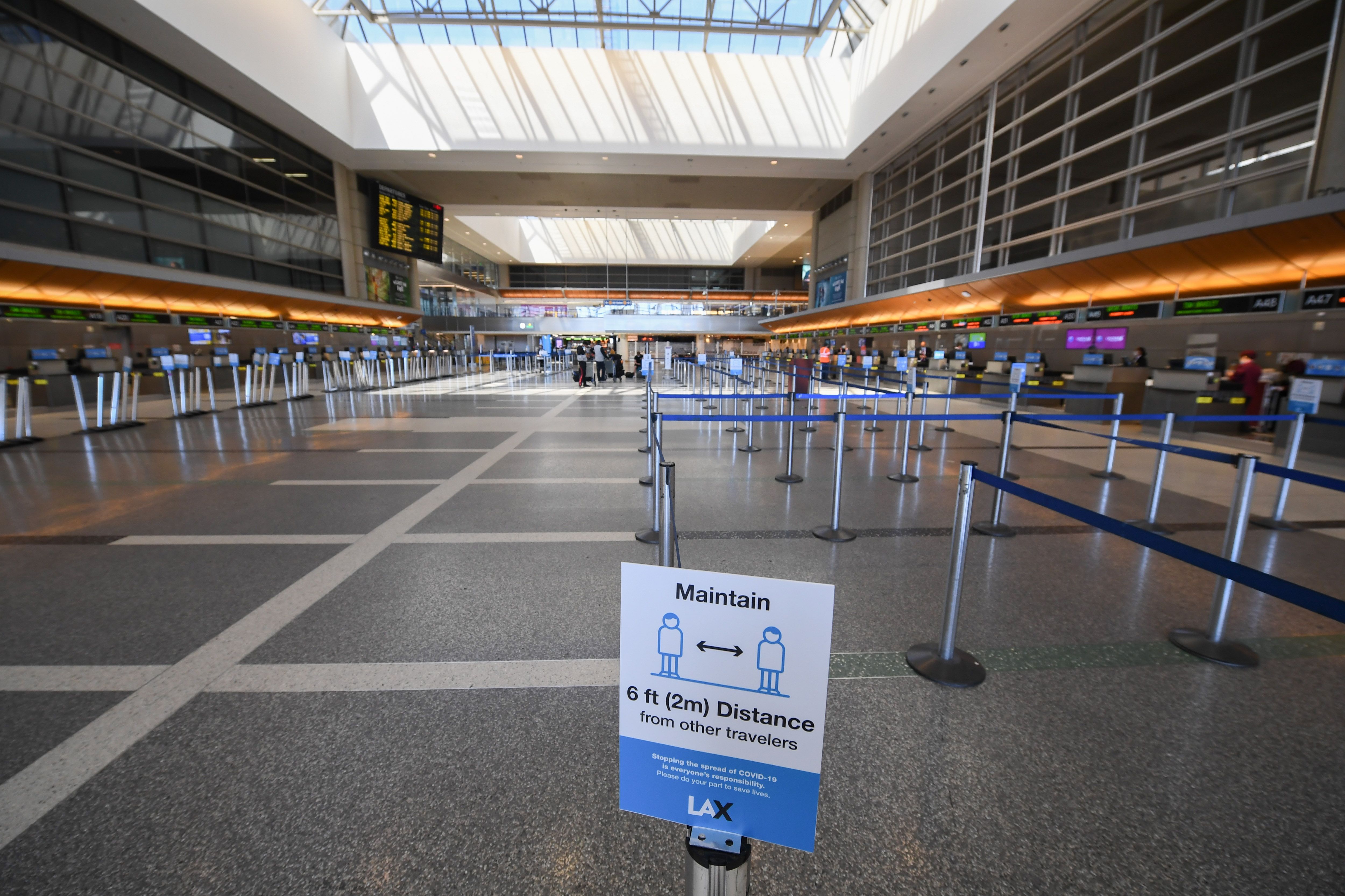 A sign advises travelers to respect social distancing at a largely empty Tom Bradley International Terminal at Los Angeles International airport on August 12, 2020 in Los Angeles during the coronavirus pandemic. - On August 11, 559,420 passengers passed through T.S.A. security checks, compared with just over 2.3 million passengers on the same day one year ago. At the same time the August 11, 2020 number is a large jump up from April 12, 2020 when only 90,510 passengers traveled out of US airports, according to U.S. Transportation Security Administration (TSA) records. (Photo by Robyn Beck / AFP) (Photo by ROBYN BECK/AFP via Getty Images)