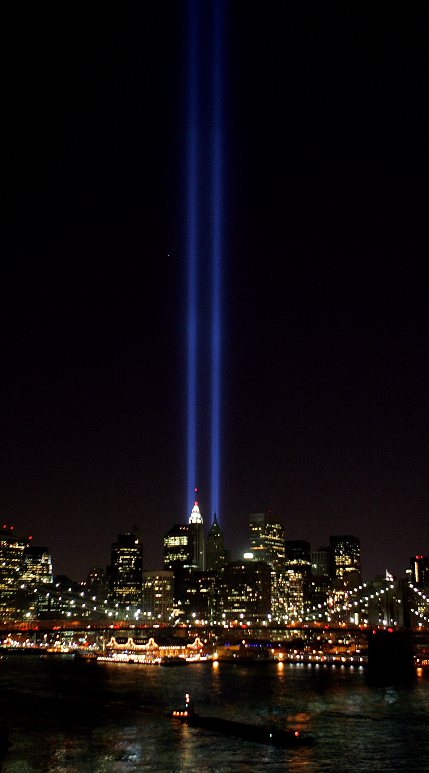 NEW YORK - SEPTEMBER 11: Beams of light shine into the sky behind the Brooklyn Bridge and above the Manhattan skyline on September 11, 2005 in New York City. The lights pay tribute to those who lost their lives when the World Trade Center was attacked four years ago. (Photo by Daniel Berehulak/Getty Images)