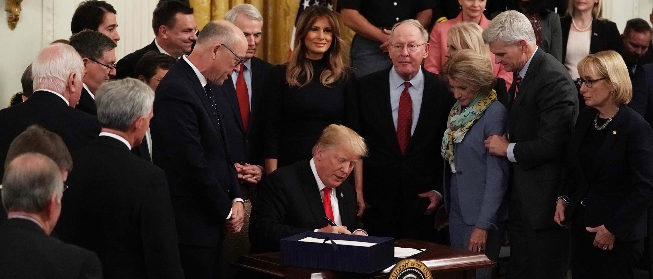 WASHINGTON, DC - OCTOBER 24: Flanked by lawmakers and first lady Melania Trump, U.S. President Donald Trump participates in a bill signing to dedicate more resources to fight the opioid crisis during an East Room event at the White House October 24, 2018 in Washington, DC.(Photo by Alex Wong/Getty Images)