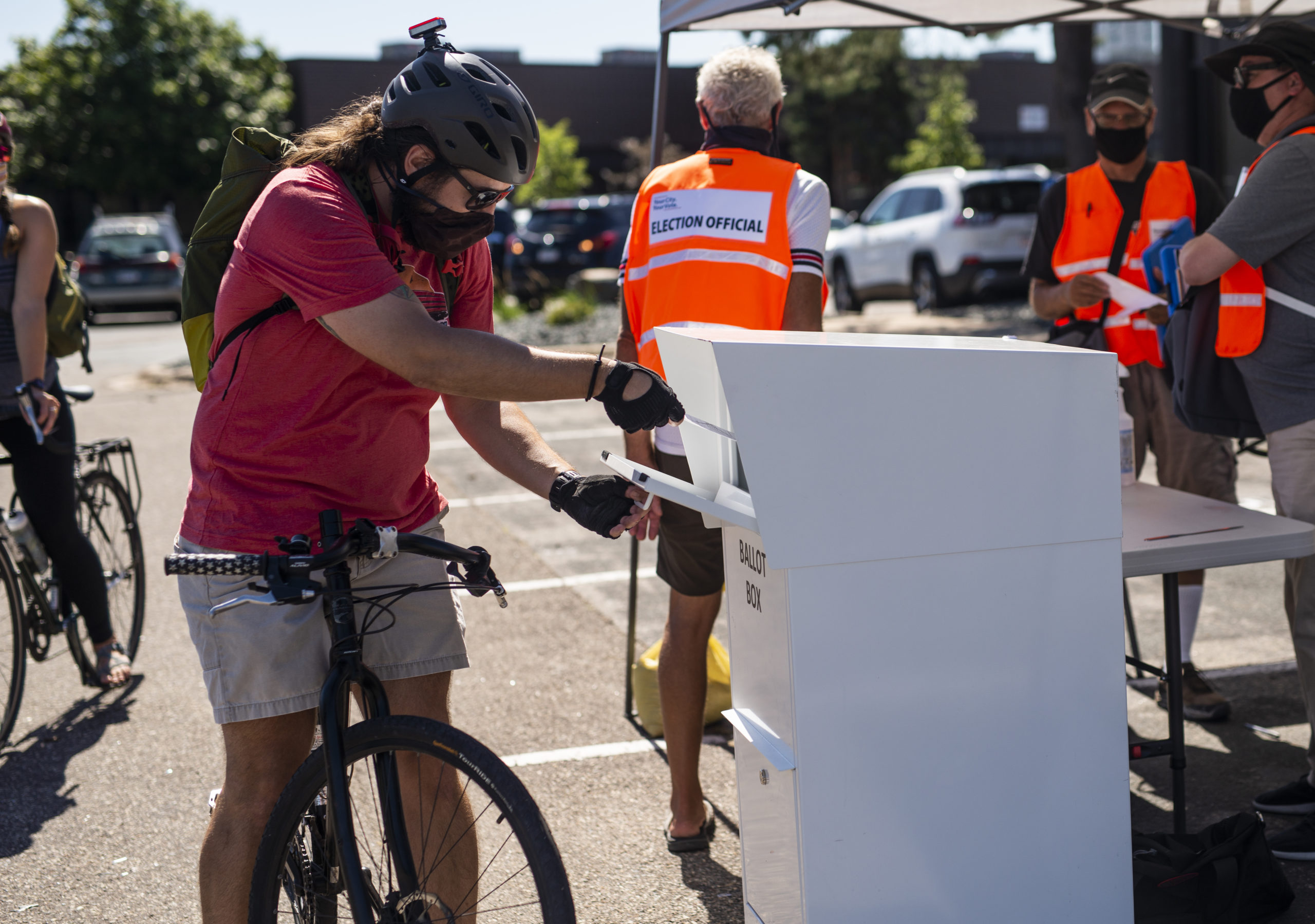 MINNEAPOLIS, MN - AUGUST 11: A voter on bicycle drops off their ballot at a drive through drop-off for absentee ballots on August 11, 2020 in Minneapolis, Minnesota. Voters in Minneapolis were able to drop off their mail-in ballots in person at two different locations, which were made available temporarily to assuage fears of delay in USPS delivery. (Photo by Stephen Maturen/Getty Images)