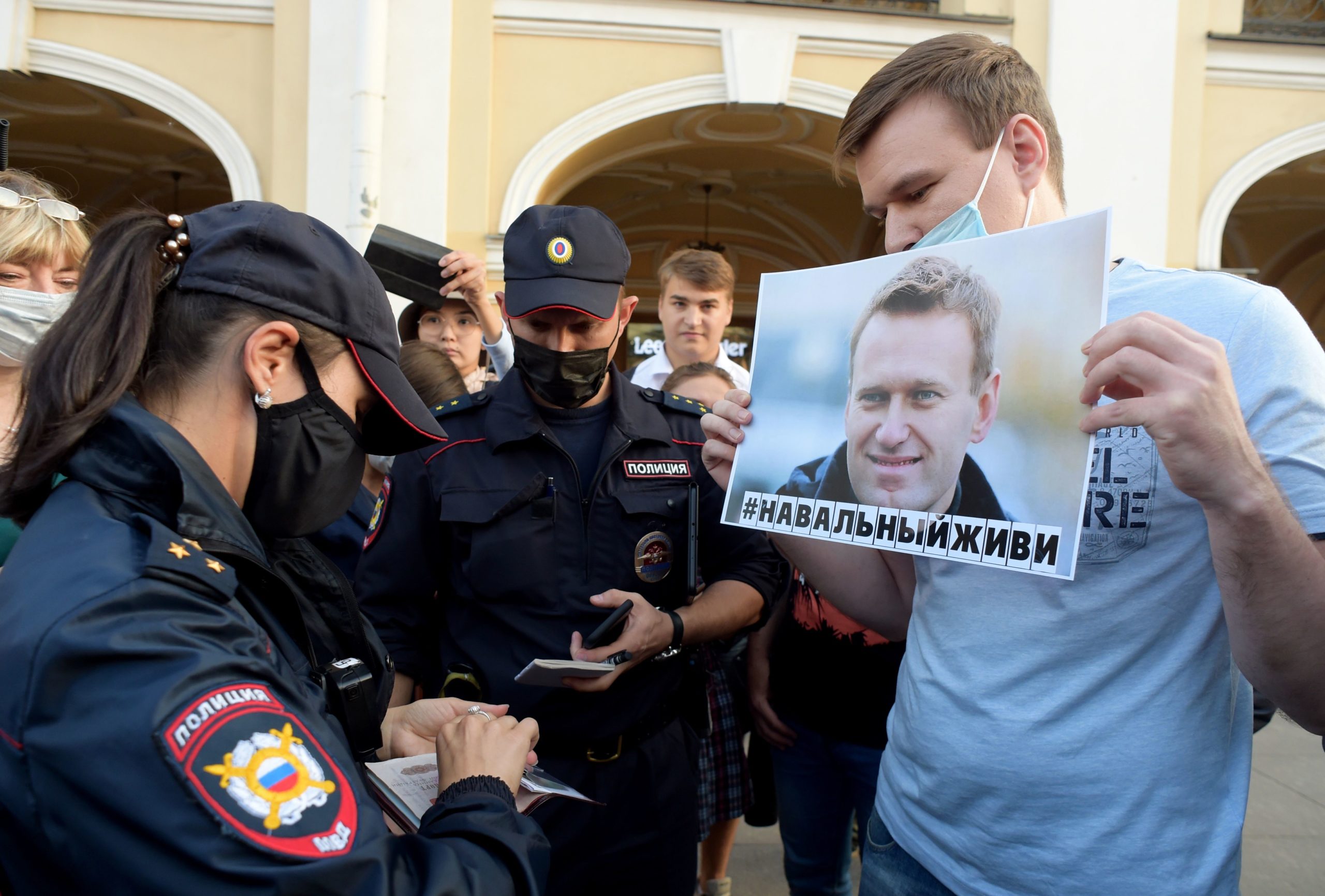 Police officers check documents of a man standing with a placard with an image of Alexei Navalny during a gathering to express support for the opposition leader after he was rushed to intensive care in Siberia suffering from what his spokeswoman said was a suspected poisoning, in downtown Saint Petersburg on August 20, 2020. (Olga Maltseva/AFP via Getty Images)