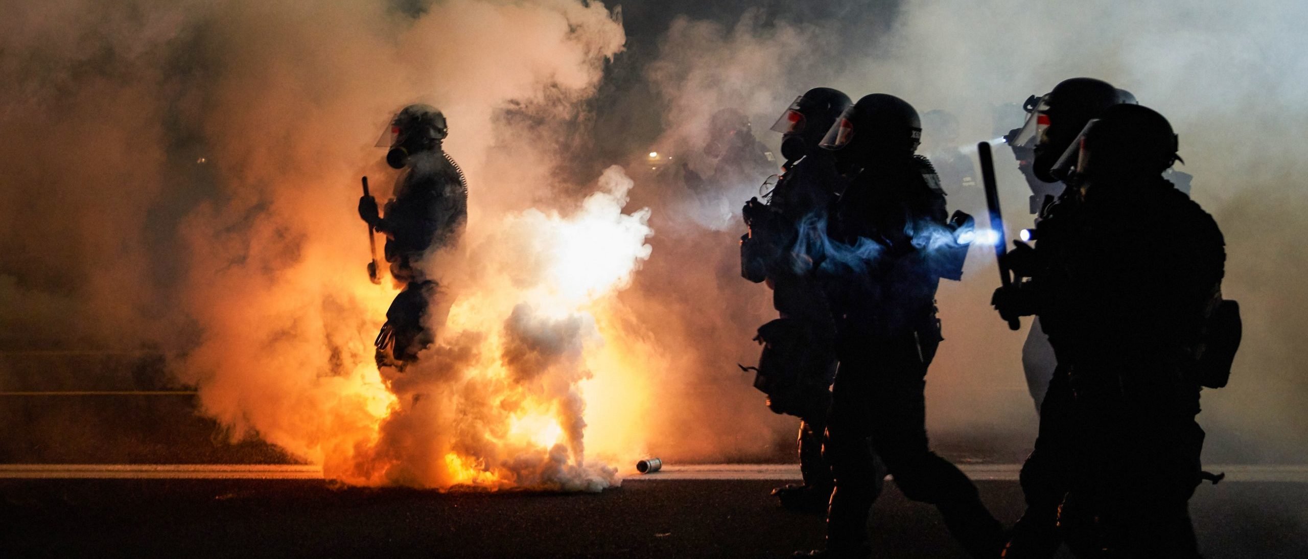 TOPSHOT - Oregon Police wearing anti-riot gear march towards protesters through tear gas smoke during the 100th day and night of protests against racism and police brutality in Portland, Oregon, on September 5, 2020. - Police arrested dozens of people and used tear gas against hundreds of demonstrators in Portland late on September 5 as the western US city marked 100 days since Black Lives Matter protests erupted against racism and police brutality. Protests in major US cities erupted after the death of African American George Floyd in May 2020 at the hands of a white police officer in Minneapolis. (ALLISON DINNER/AFP via Getty Images)