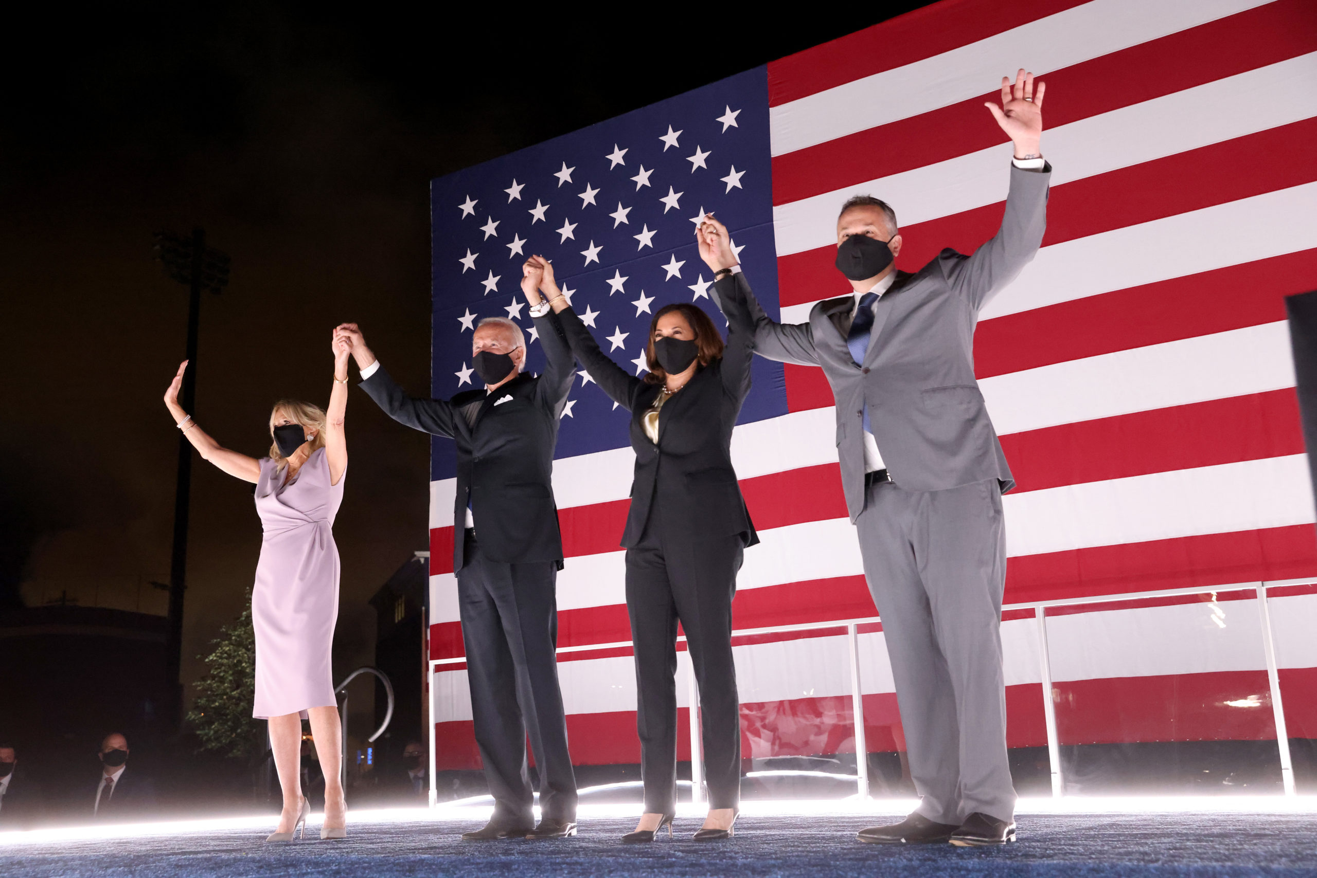 WILMINGTON, DELAWARE - AUGUST 20: Democratic presidential nominee Joe Biden, his wife Dr. Jill Biden, Democratic Vice Presidential nominee Kamala Harris and her husband Douglas Emhoff raise their arms on stage outside the Chase Center after Biden delivered his acceptance speech on the fourth night of the Democratic National Convention from the Chase Center on August 20, 2020 in Wilmington, Delaware. The convention, which was once expected to draw 50,000 people to Milwaukee, Wisconsin, is now taking place virtually due to the coronavirus pandemic. (Photo by Win McNamee/Getty Images)