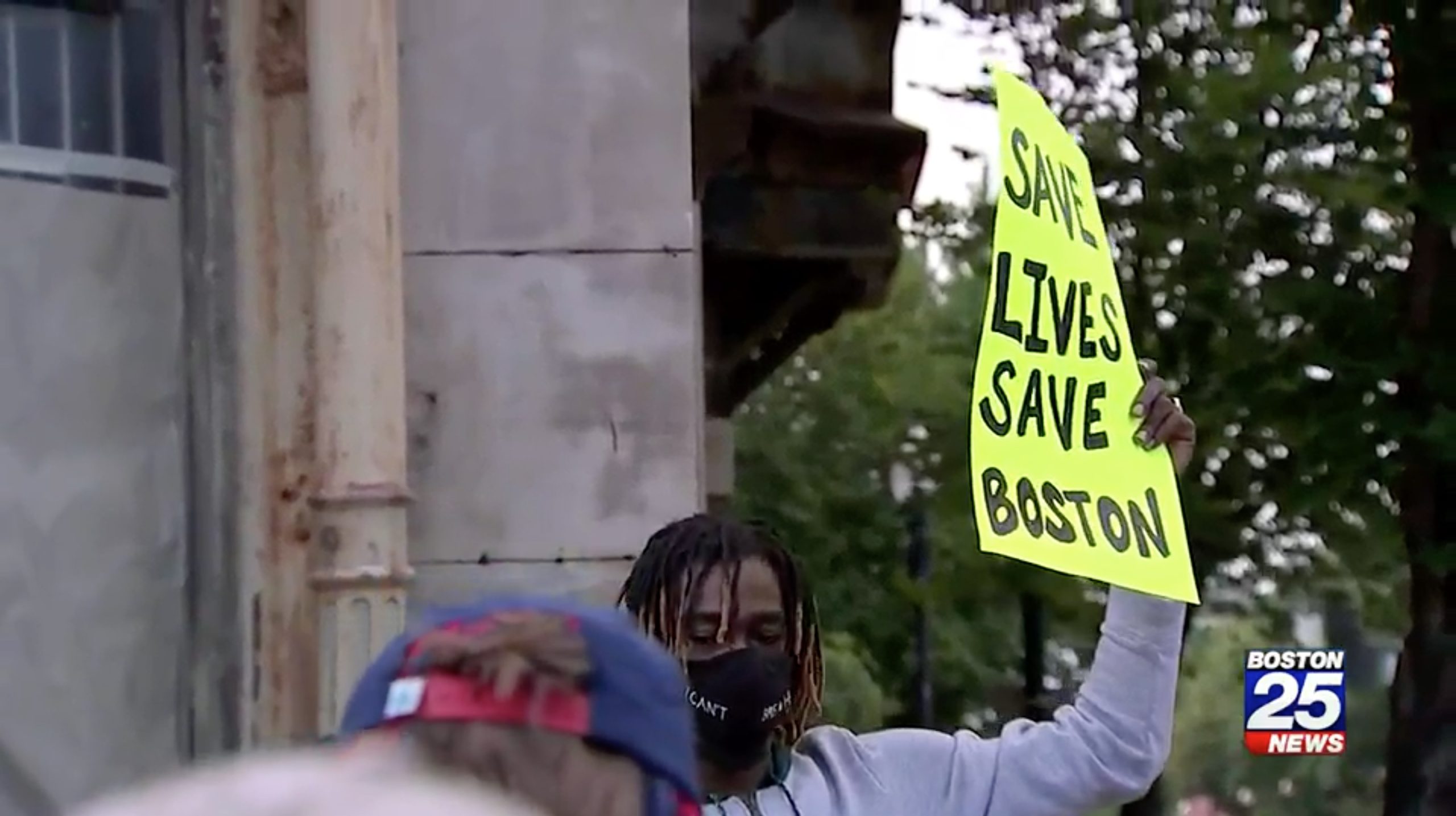 A demonstrator holds a sign that says "Save Lives Save Boston" during a protest against the conditions of "Methadone Mile" in Boston Thursday. (Boston 25 News/Video screenshot)