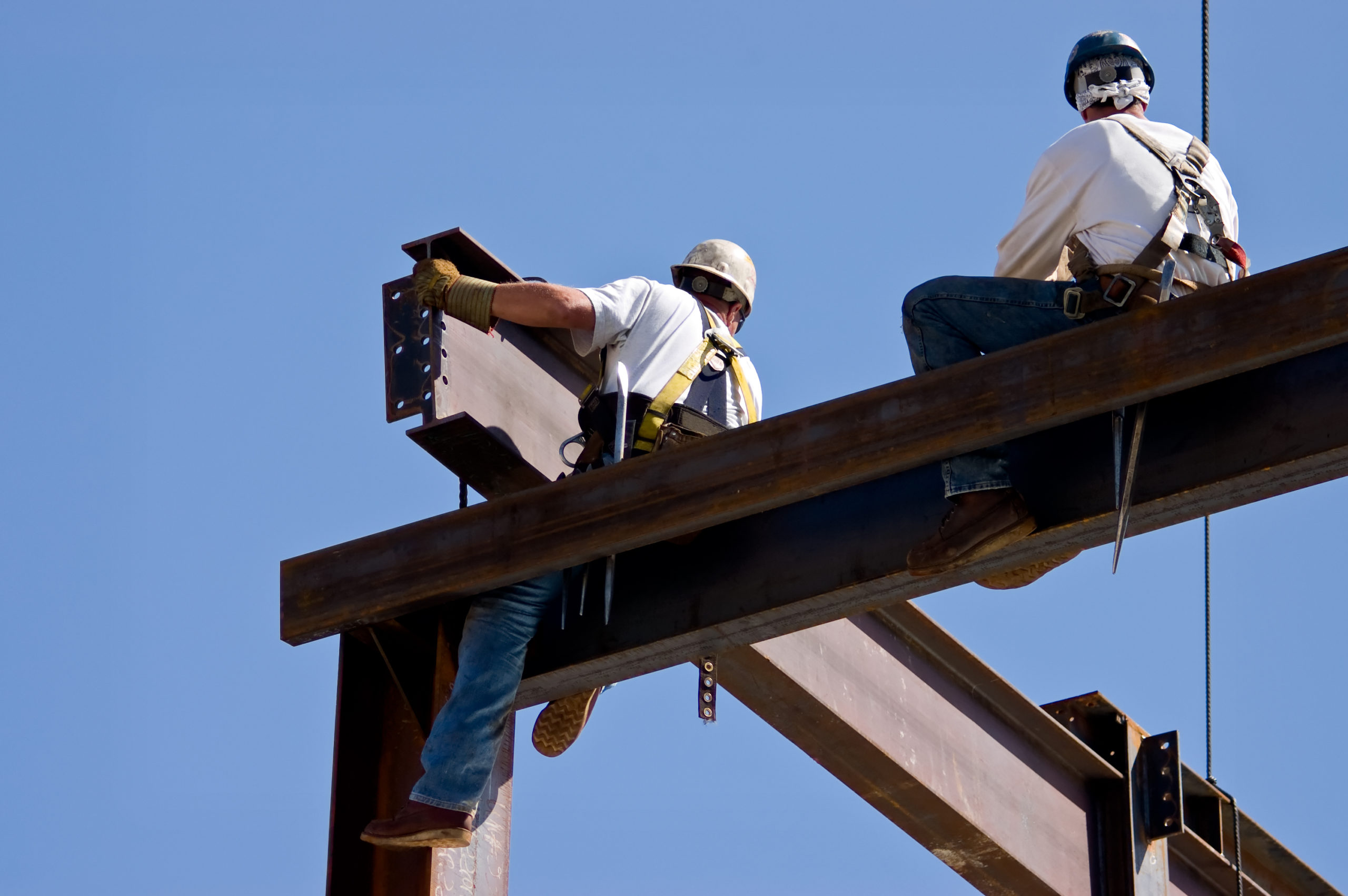 Two iron workers atop a beam at a construction site. (Dwight Smith/Shutterstock)