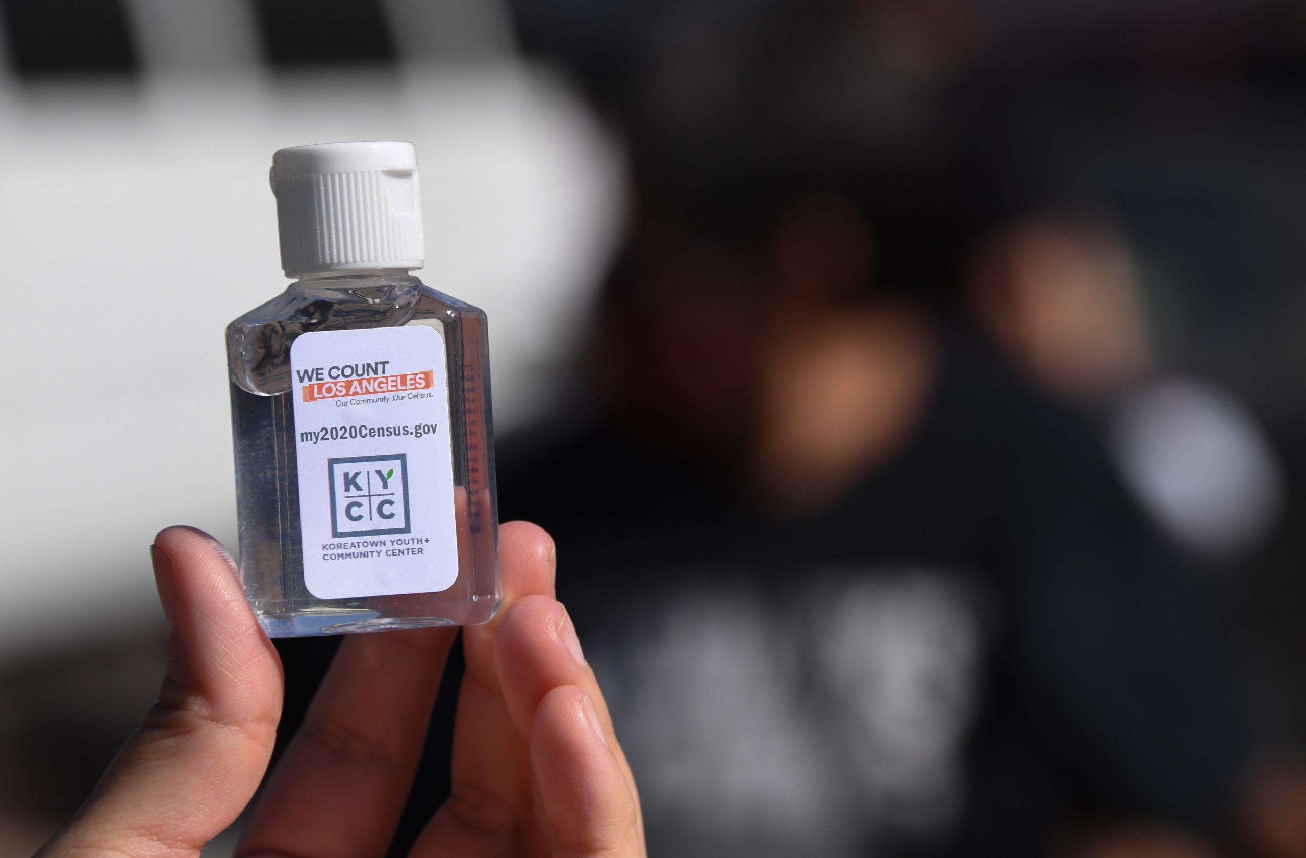 A volunteer displays a bottle of hand sanitzer labeled with information about the US Census which she is passing out to encourage people to complete the Census, at a food distribution bank for people facing economic hardship or food insecurity, in a church parking lot in Los Angeles, California, August 10, 2020 amid the COVID-19 pandemic. - The result of the Census, which the Census Bureau announced it would end one month early, on September 30, directly affects the amount of funding a community receives for services including public schools, hospitals and fire departments. (Photo by Robyn Beck / AFP) (Photo by ROBYN BECK/AFP via Getty Images)