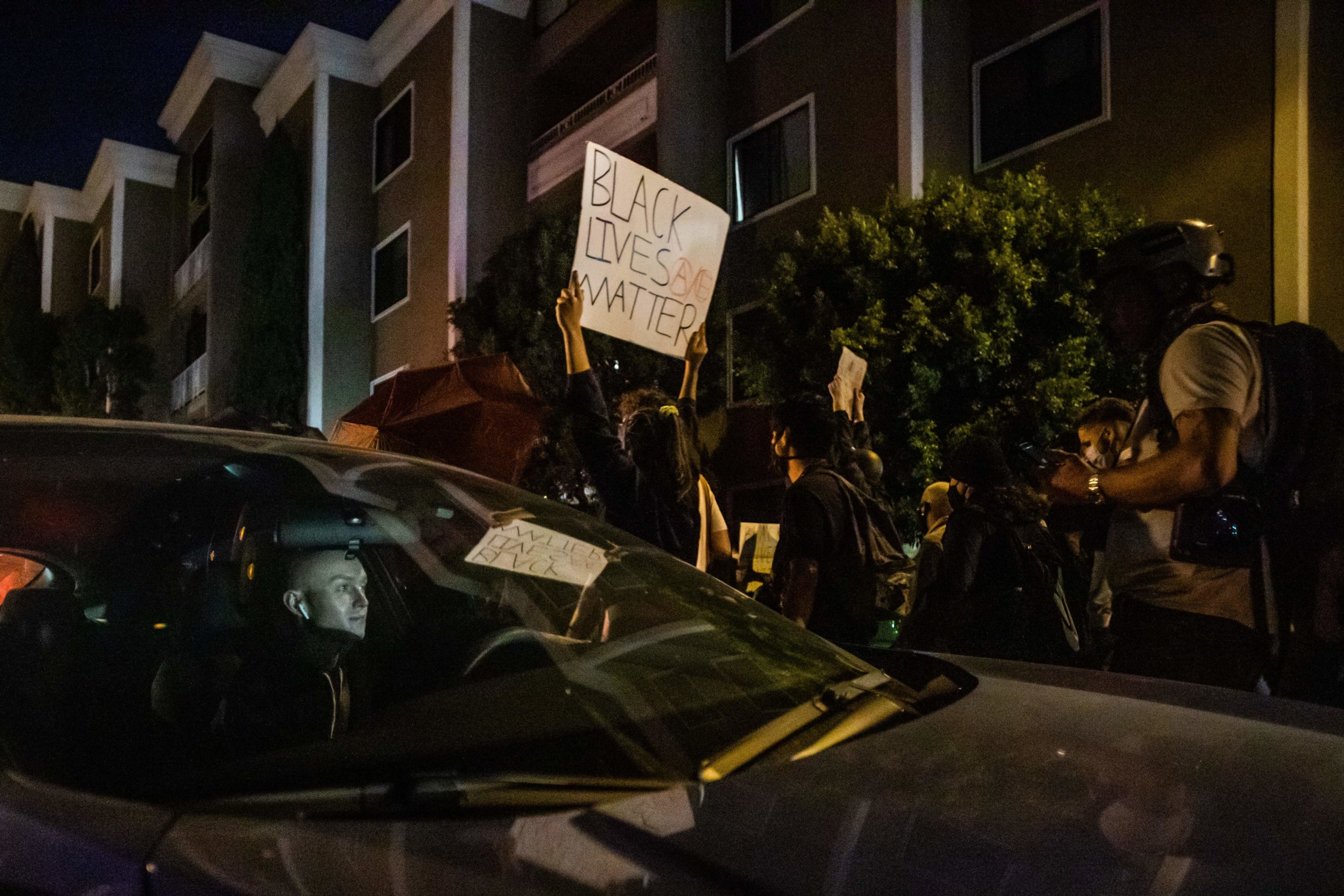 A driver stuck in the protest watches demonstrators passing by his car as they manifest their discontent over the lack of criminal charges in the police killing of Breonna Taylor in West Hollywood, California on September 25, 2020. - The family of Breonna Taylor today, September 25, demanded that US authorities release grand jury transcripts showing why no police will face direct criminal charges over her death, which has once again galvanized protesters angry about racism and police brutality in America. (Photo by Apu GOMES / AFP) (Photo by APU GOMES/AFP via Getty Images)