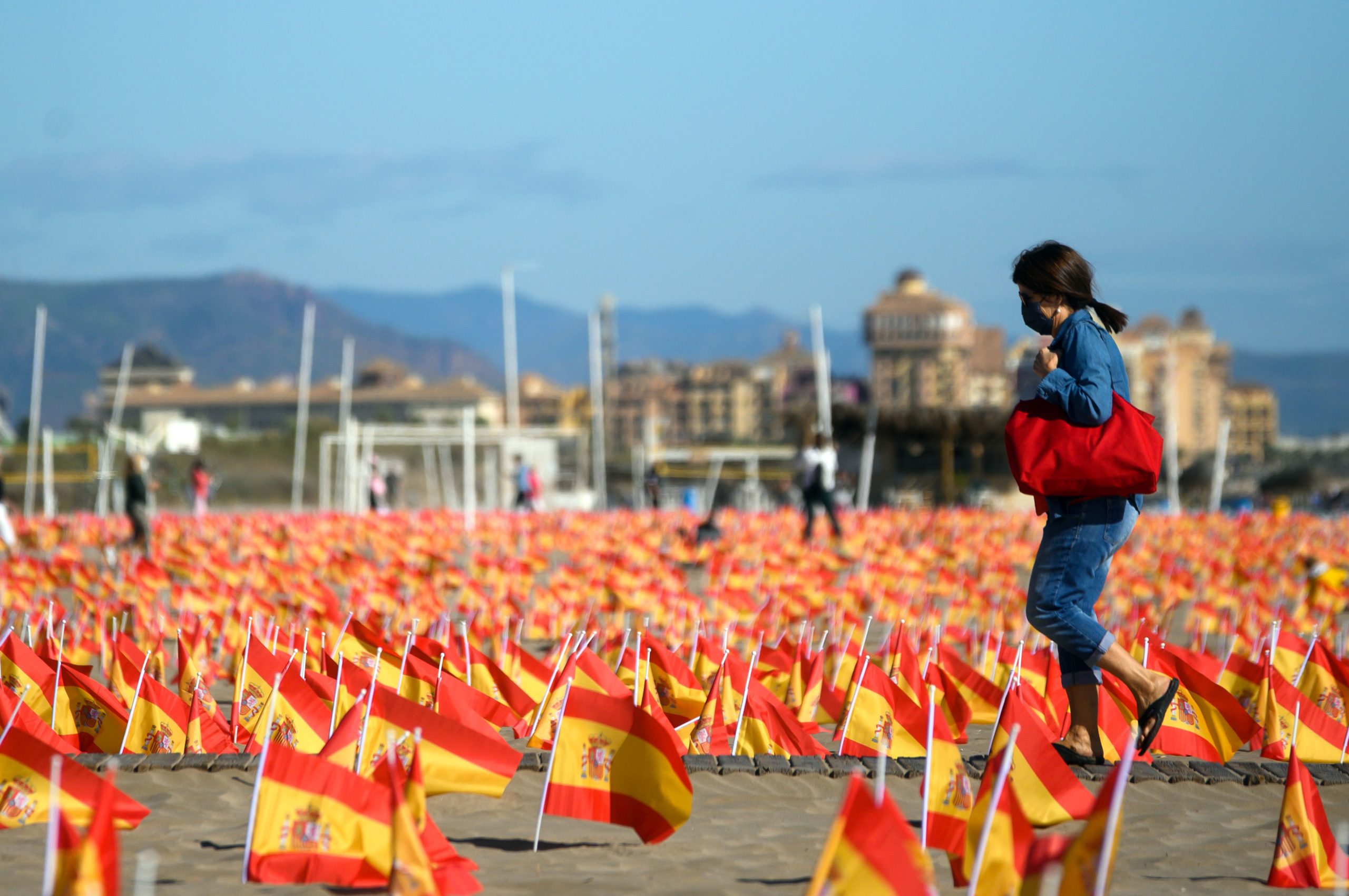 A woman walks among thousands of Spanish flags, representing the Spanish victims of coronavirus, on Patacona beach in Valencia, on Oct. 4. (Jose Jordan/AFP via Getty Images)