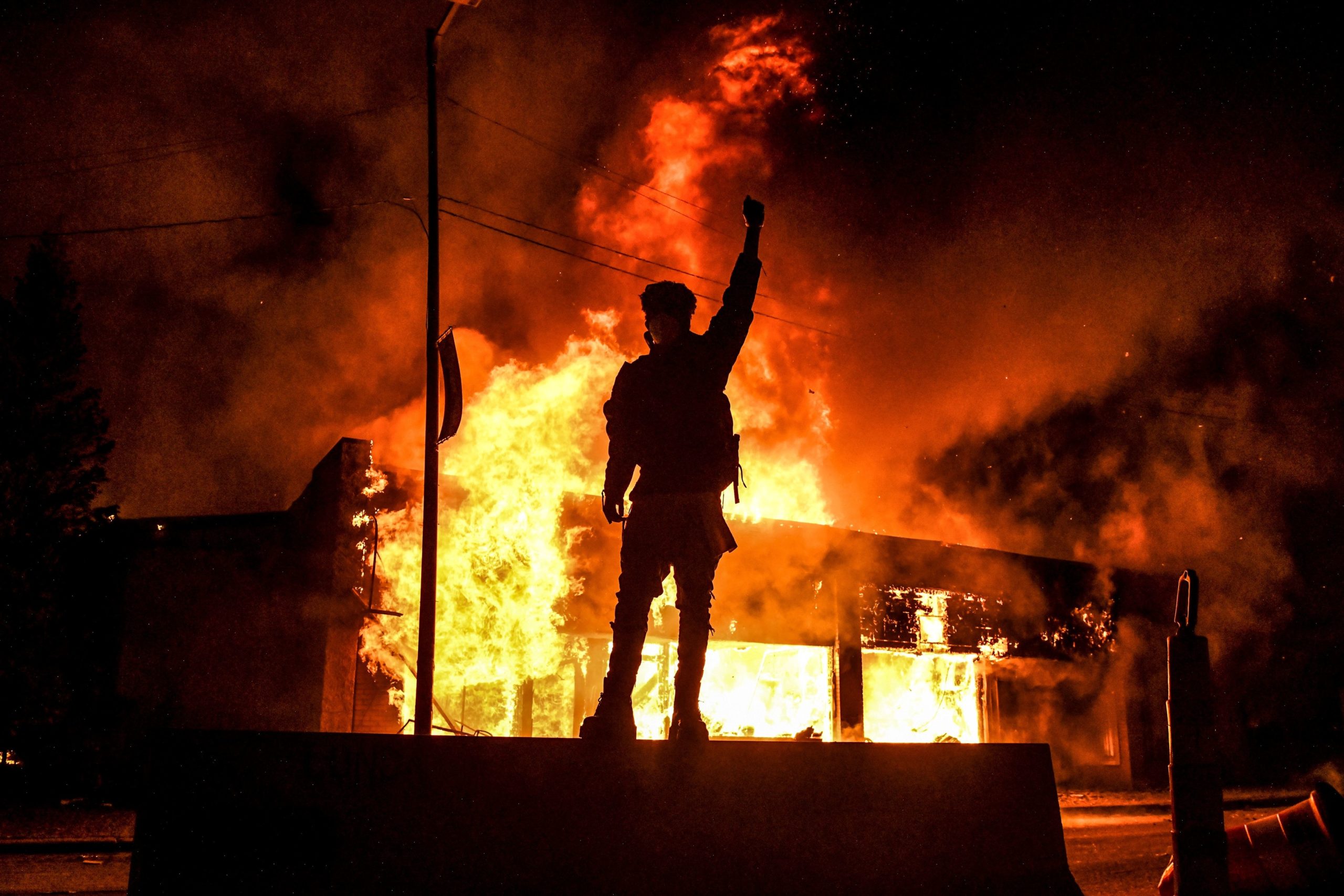 TOPSHOT - A protester reacts standing in front of a burning building set on fire during a demonstration in Minneapolis, Minnesota, on May 29, 2020, over the death of George Floyd, a black man who died after a white policeman kneeled on his neck for several minutes. - Violent protests erupted across the United States late on May 29 over the death of a handcuffed black man in police custody, with murder charges laid against the arresting Minneapolis officer failing to quell seething anger. (CHANDAN KHANNA/AFP via Getty Images)