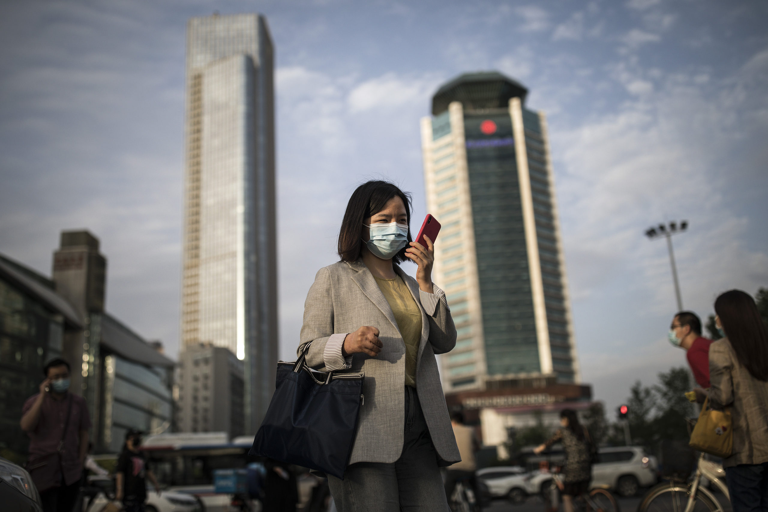 WUHAN, CHINA - MAY 11: (CHINA OUT) A women wears a mask while uses iPhone pass the crossroads on May 11, 2020 in Wuhan, China. The government has begun lifting outbound travel restrictions after almost 11 weeks of lockdown to stem the spread of COVID-19. (Photo by Getty Images)