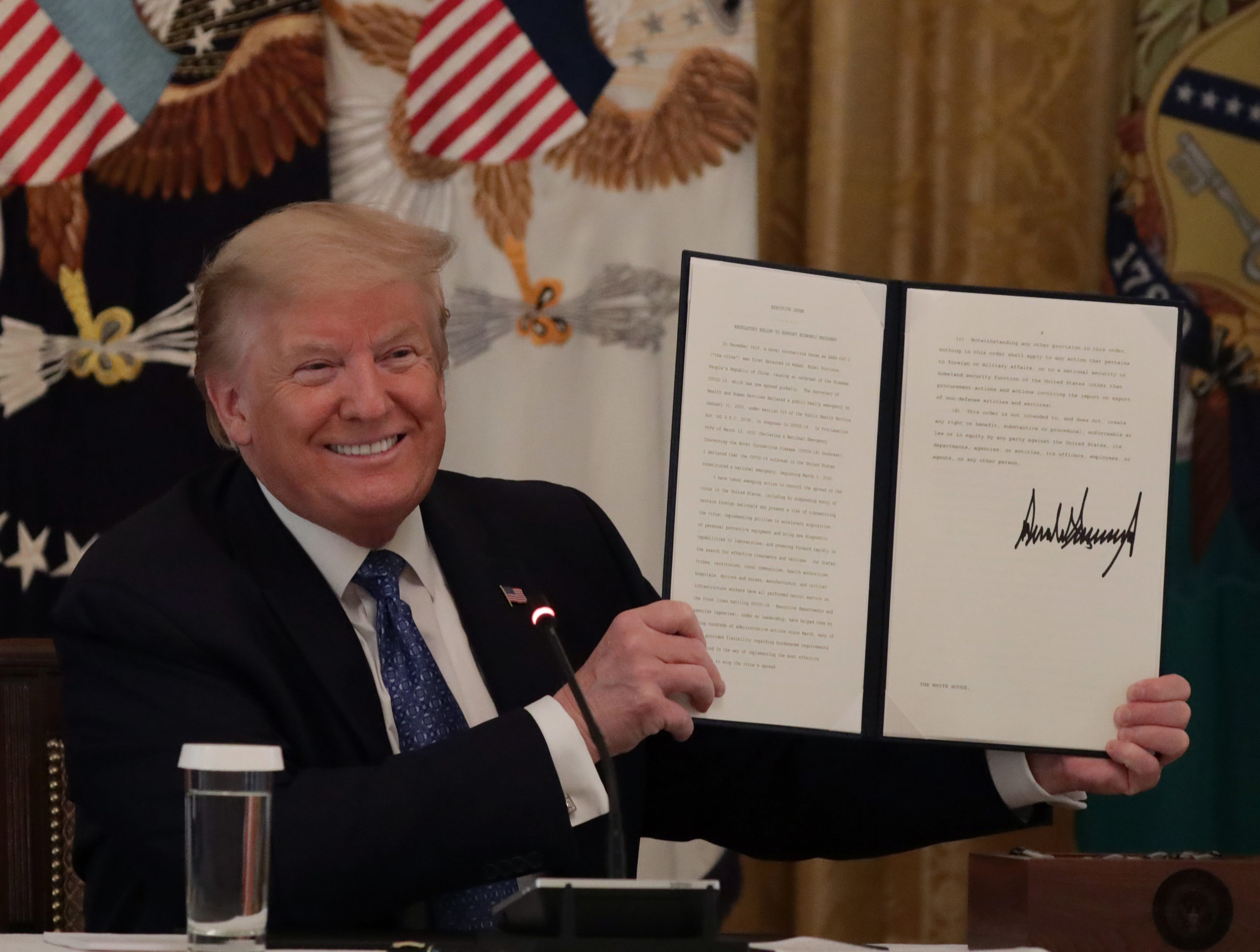 WASHINGTON, DC - MAY 19: U.S. President Donald Trump holds up a copy of an executive order he signed on DOT deregulation, during a meeting with his cabinet in the East Room of the White House on May 19, 2020 in Washington, DC. (Photo by Alex Wong/Getty Images)