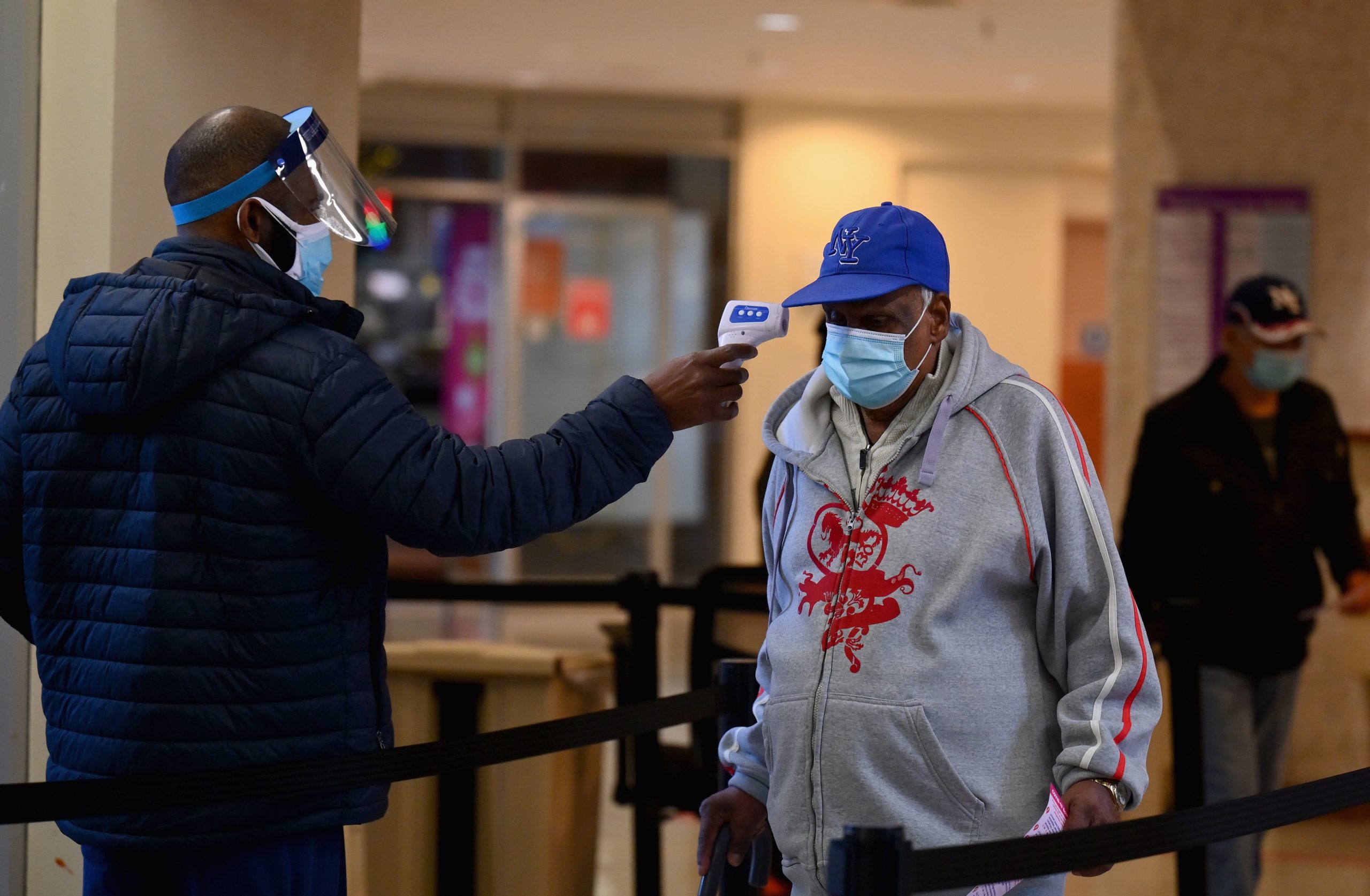 A staff member checks the temperature of a visitor at Woodhull Medical and Mental Health Center on Dec. 1 in New York City. (Angela Weiss/AFP via Getty Images)