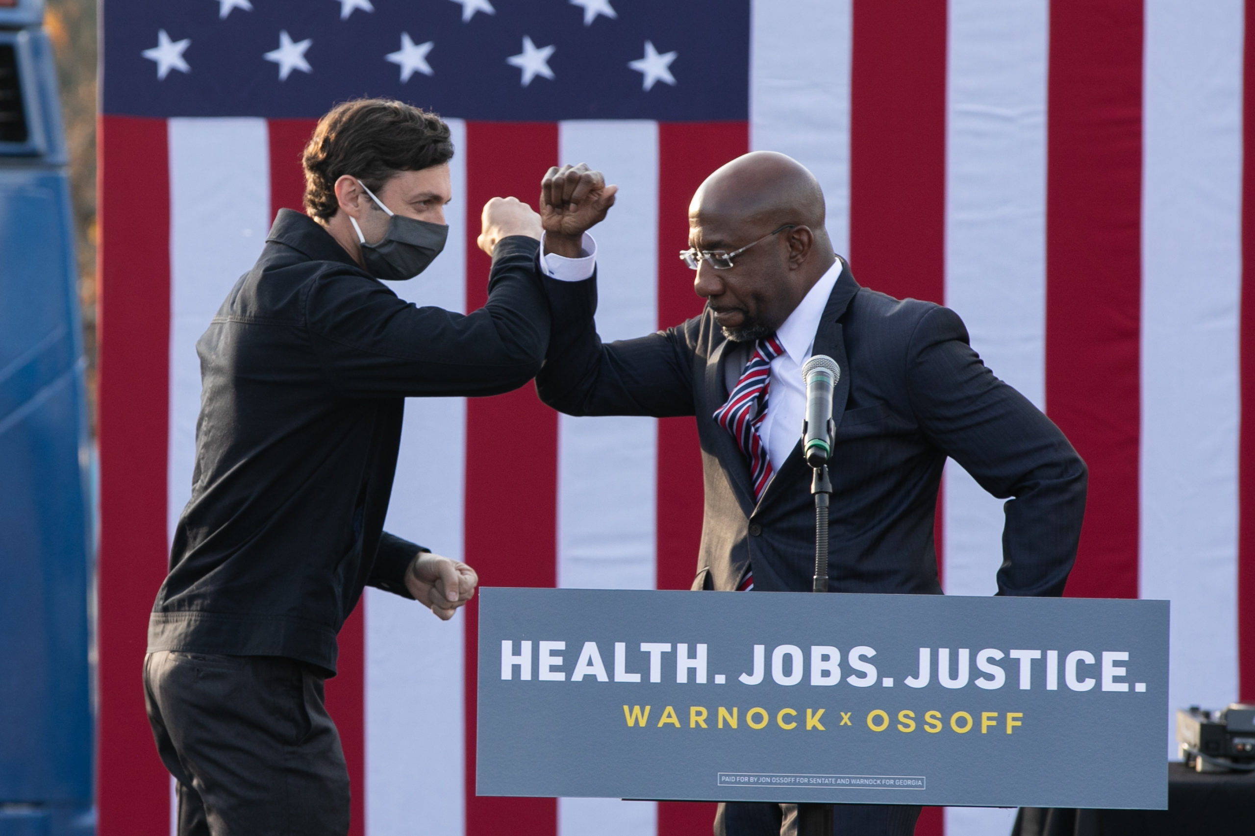 STONECREST, GA - DECEMBER 28: Georgia Democratic Senate candidates Raphael Warnock (R) and Jon Ossoff (L) bump elbows during a "It's Time to Vote" drive-in rally on December 28, 2020 in Stonecrest, Georgia. With a week until the January 5th runoff election that will determine control of the Senate, candidates continue to campaign throughout Georgia. (Photo by Jessica McGowan/Getty Images)