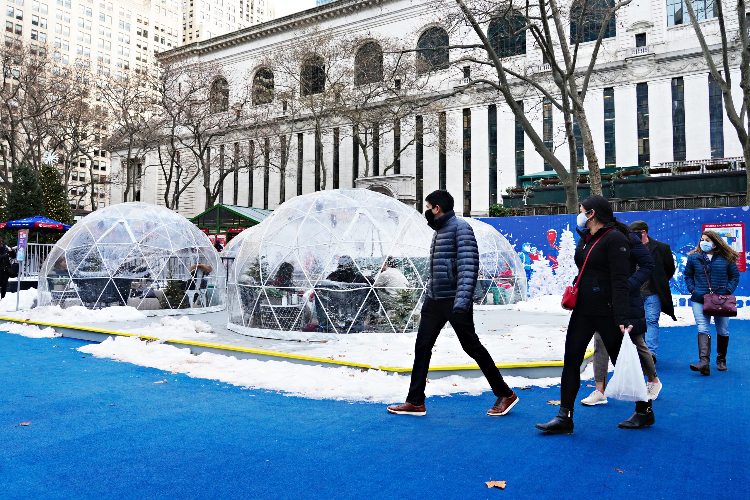 People walk by igloo dining tents at Bank of America Winter Village in Bryant Park on December 23, 2020 in New York City. The pandemic continues to burden restaurants and bars as businesses struggle to thrive with evolving government restrictions and social distancing plans which impact keeping businesses open yet challenge profitability. (Photo by Cindy Ord/Getty Images)